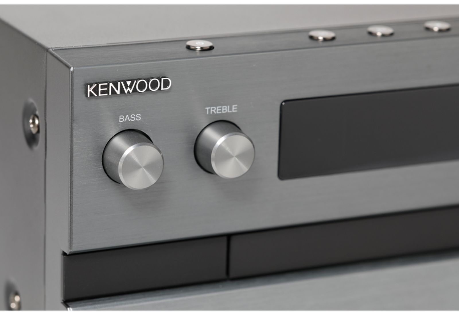 Un primo piano di un ricevitore stereo Kenwood. Ha manopole con etichetta Bass e Treble. Il dispositivo è argento e nero.