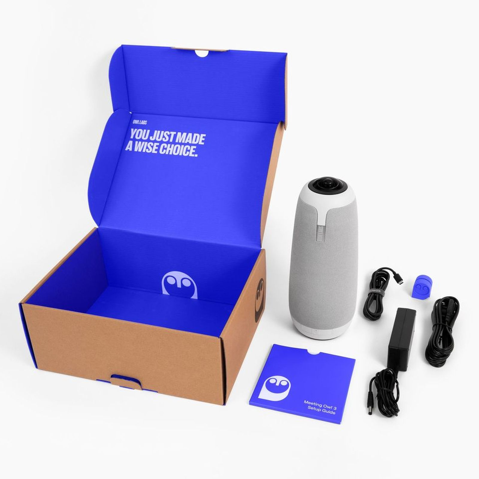 Offene Box mit blauem Innenraum, ein Lautsprecher, Kabel, Netzteil und eine Installationsanleitung auf weißer Oberfläche.