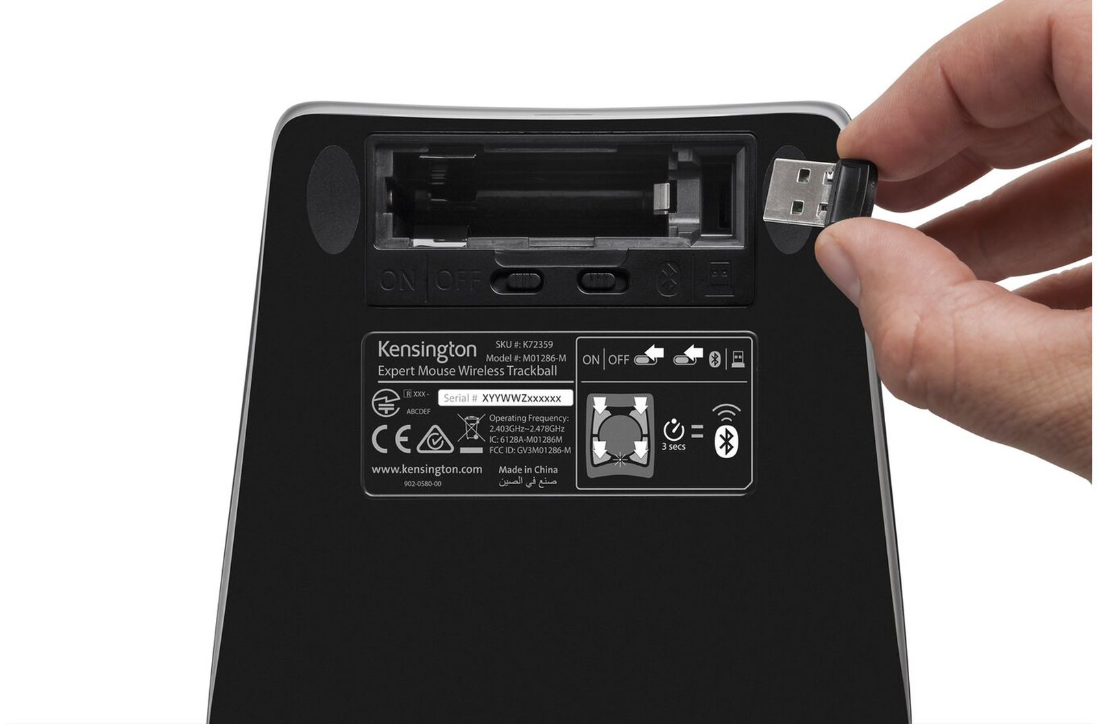 A hand inserts a USB receiver into a black Kensington mouse. The mouse has an on/off switch and product info.