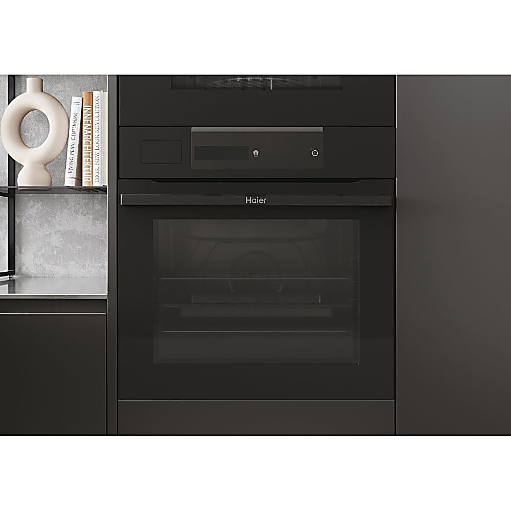 Un moderno forno nero Haier integrato in un mobile da cucina scuro, con porta a vetro e pannello di controllo. Una mensola con libri e un vaso.