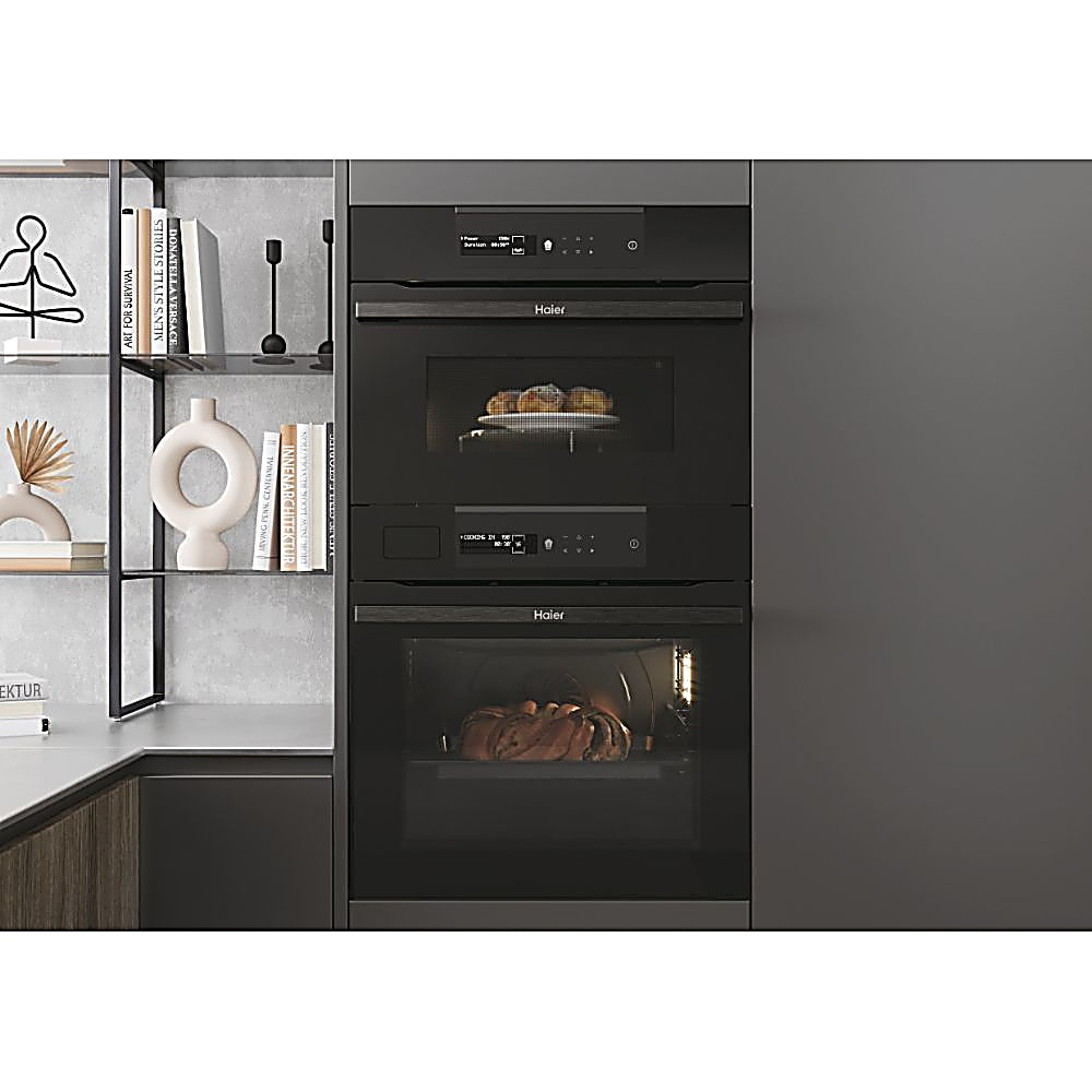 Una cucina moderna con elettrodomestici Haier integrati: microonde e forno, che mostrano prodotti da forno. Scaffali mostrano libri e decorazioni.