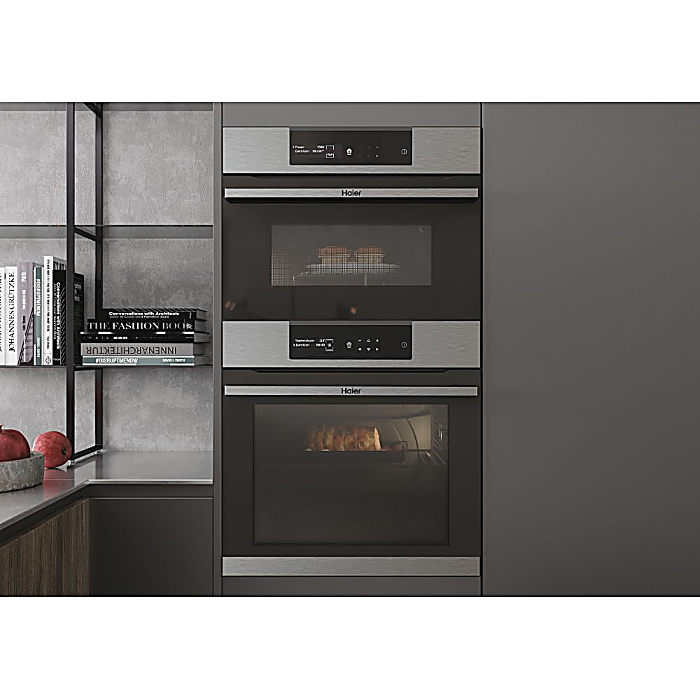 Una cucina moderna con forno e microonde Haier integrati. Librerie e piano d'appoggio a sinistra. Il forno mostra cibo.