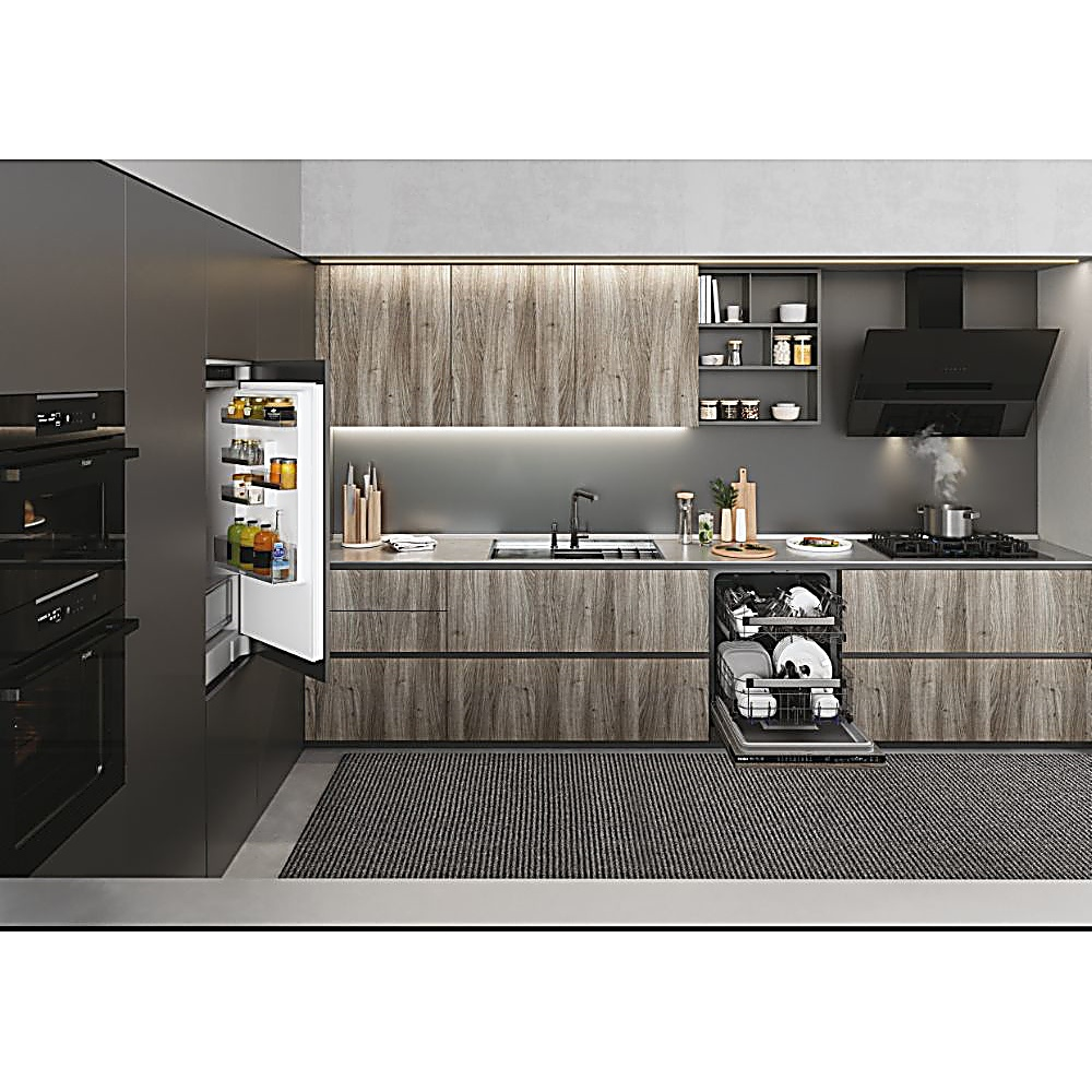 Nowoczesna kuchnia z otwartą lodówką, zmywarką, kuchenką i drewnianymi szafkami. Na podłodze dywan. Produkty spożywcze w lodówce.