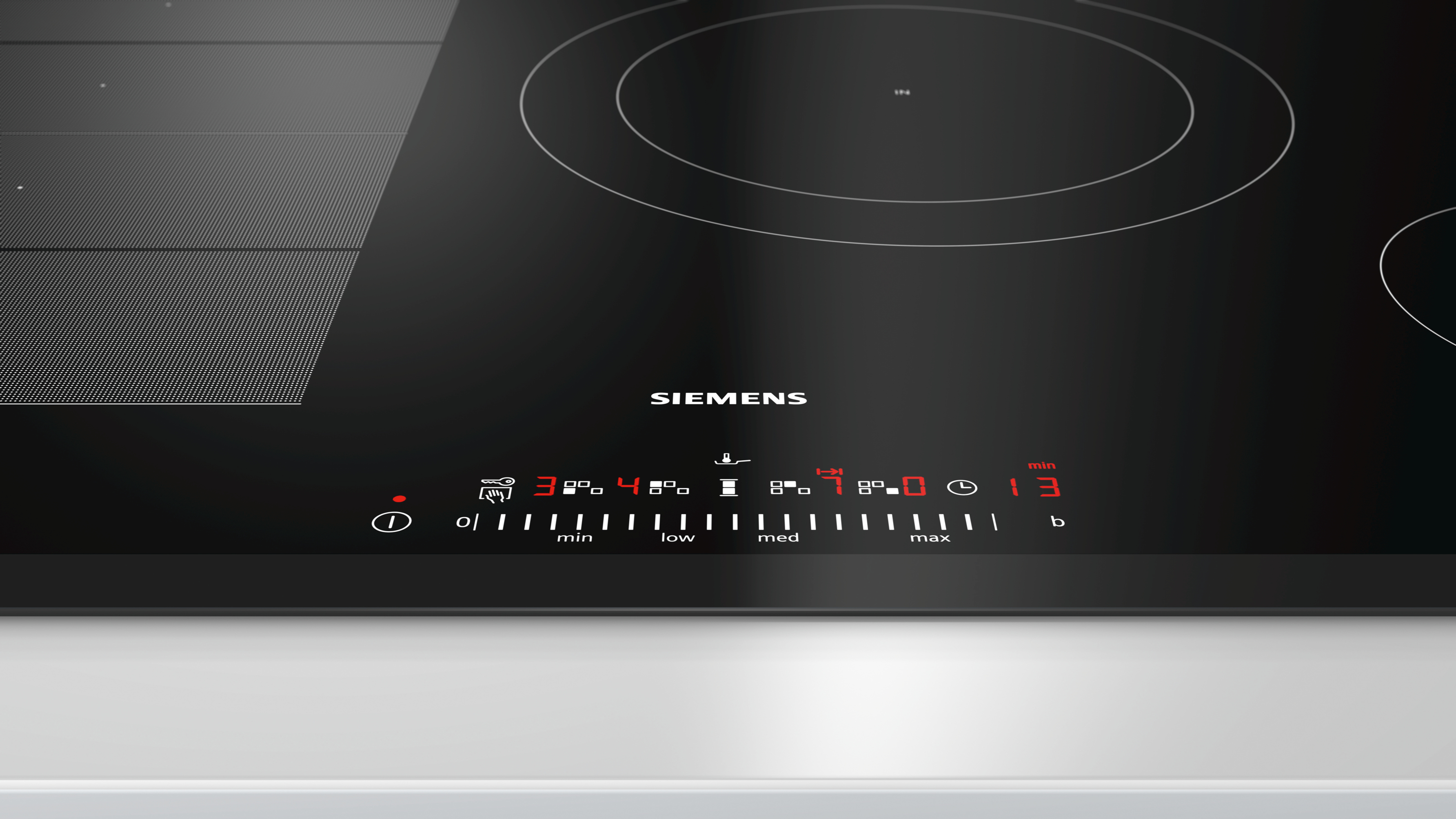 Un piano cottura a induzione Siemens nero con comandi rossi illuminati. Il display mostra timer, livelli di potenza e impostazioni.