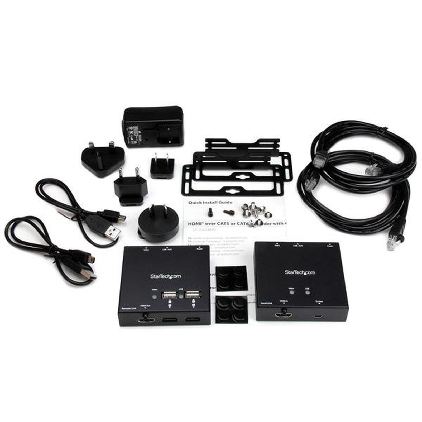 Un surtido de componentes electrónicos negros, incluidos adaptadores, cables y dos cajas con el logotipo de StarTech.com, están dispuestos sobre una superficie blanca.