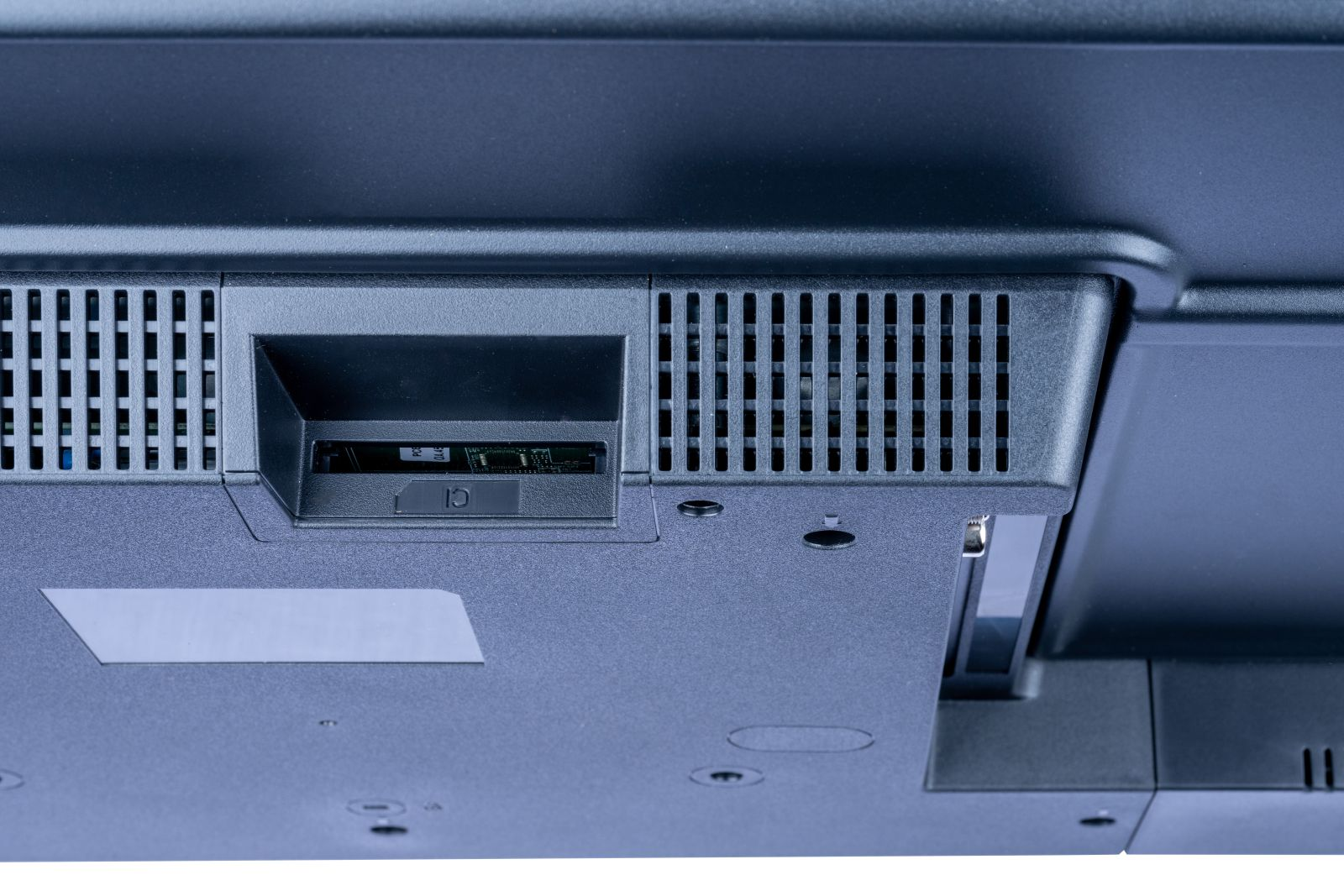 Zbliżenie czarnego urządzenia elektronicznego z otworami wentylacyjnymi, gniazdem na kartę i srebrną etykietą.