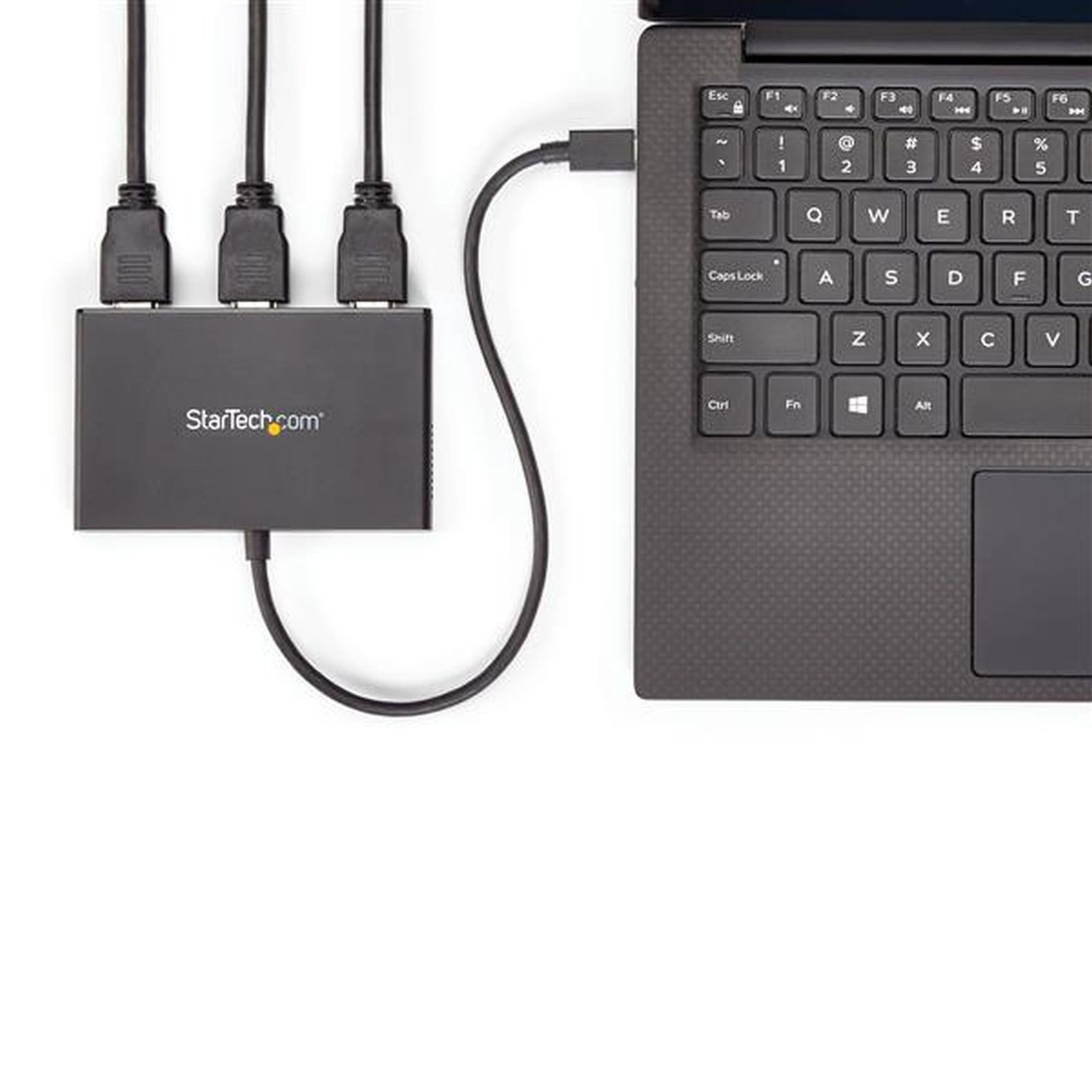 Una computadora portátil está conectada a un concentrador StarTech por USB. Tres cables HDMI están enchufados al concentrador.