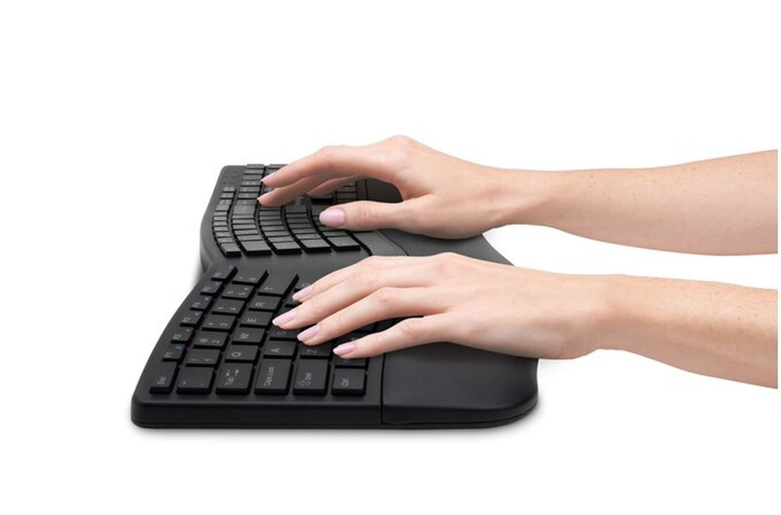 Manos tecleando en un teclado ergonómico negro. El teclado está dividido y las manos están posicionadas para escribir cómodamente.