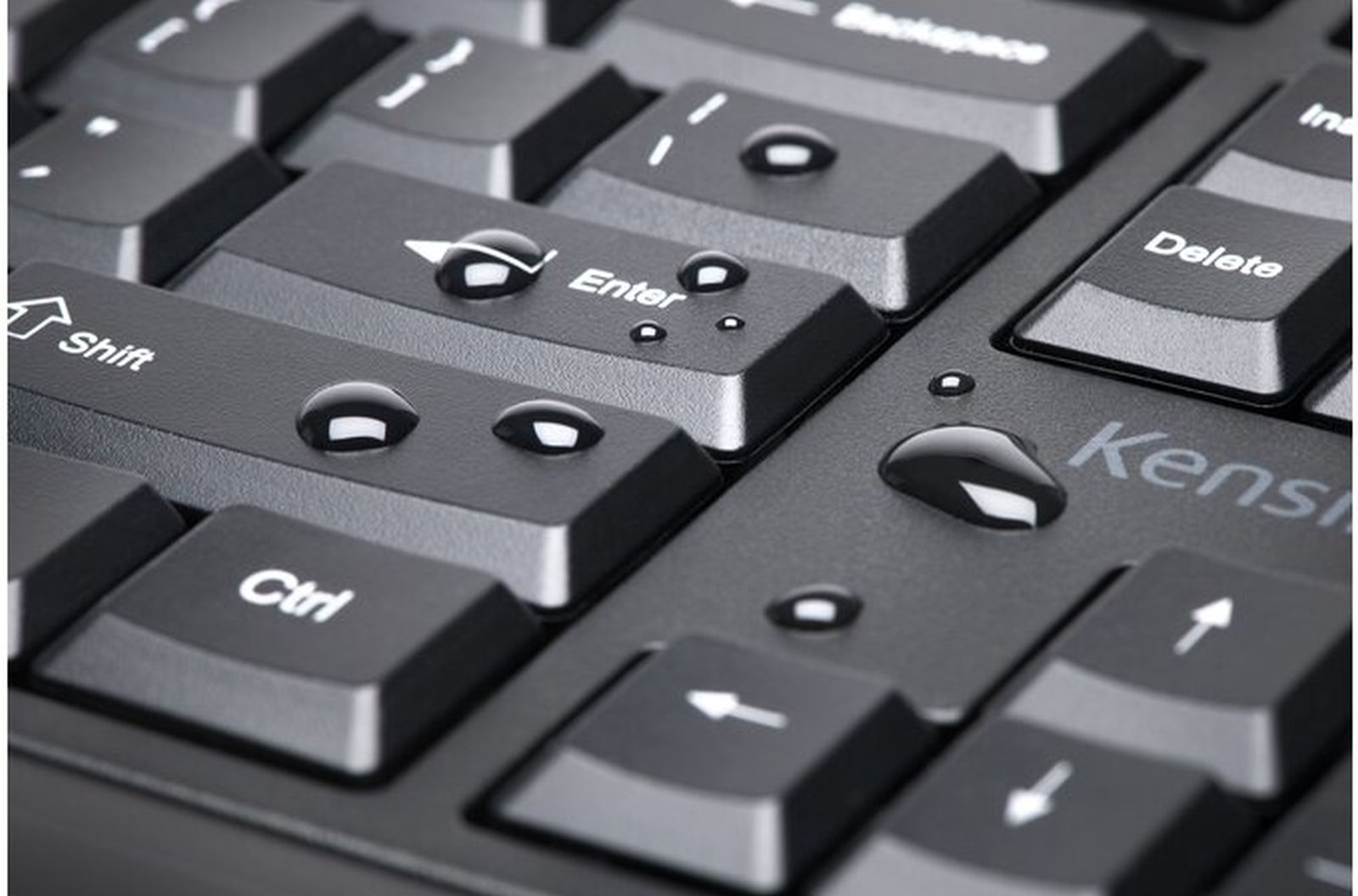 Primer plano de un teclado negro con gotas de agua en las teclas. Se ven teclas como Enter, Shift y Ctrl.