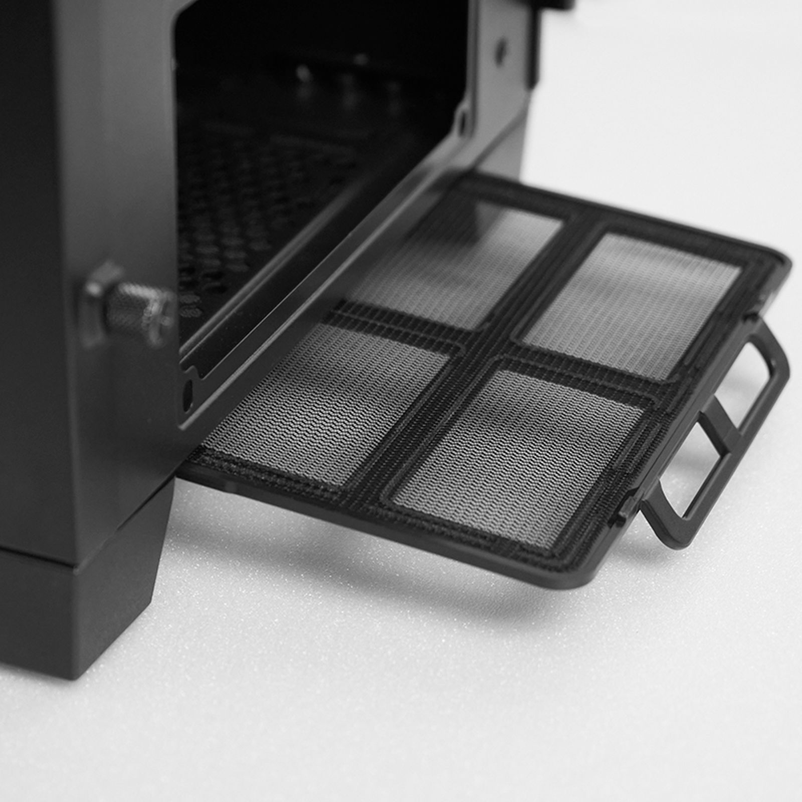 Czarny filtr przeciwkurzowy obudowy komputera wyciągnięty. Panel z siatki z uchwytem. Białe tło.