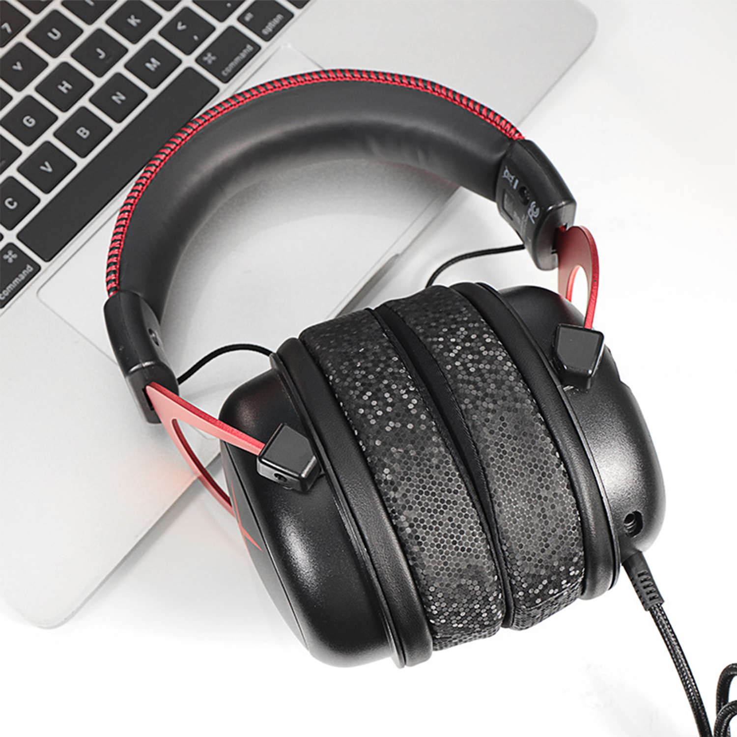 Cuffie da gioco nere e rosse su un laptop. Le cuffie hanno grandi padiglioni e un archetto imbottito. La tastiera è visibile.
