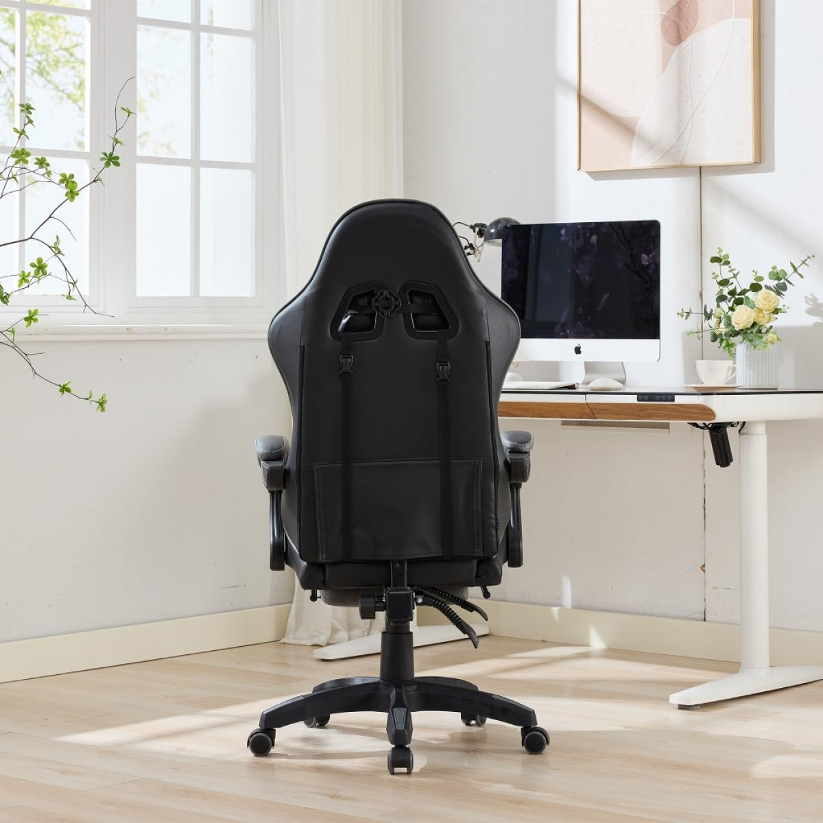 Ein schwarzer Gaming-Stuhl ist abgewandt. Dahinter ein Schreibtisch mit Computer und Blumen, neben einem Fenster. Die Wand ist weiß.