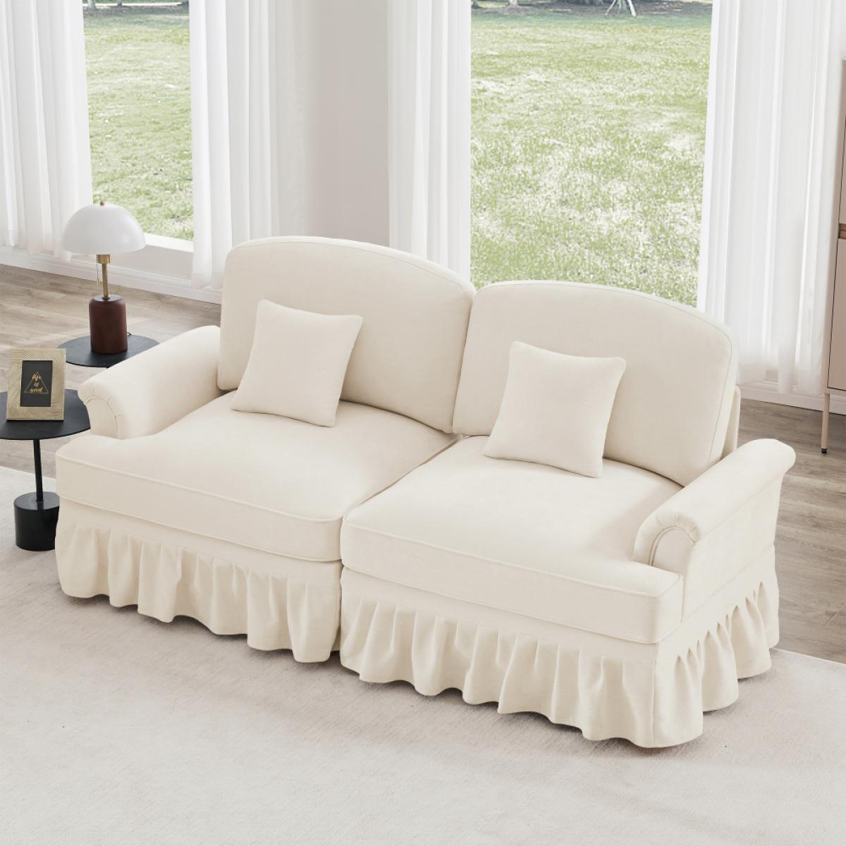Cremefarbenes Sofa mit zwei Kissen, Rüschenrock, auf einem weißen Teppich. Fenster mit transparenten Vorhängen. Grünes Gras draußen.