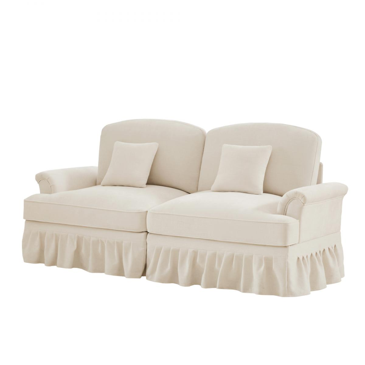 Cremefarbenes Sofa mit zwei Kissen und Rüschenrock. Es hat gebogene Arme und Rücken sowie zwei quadratische Kissen.