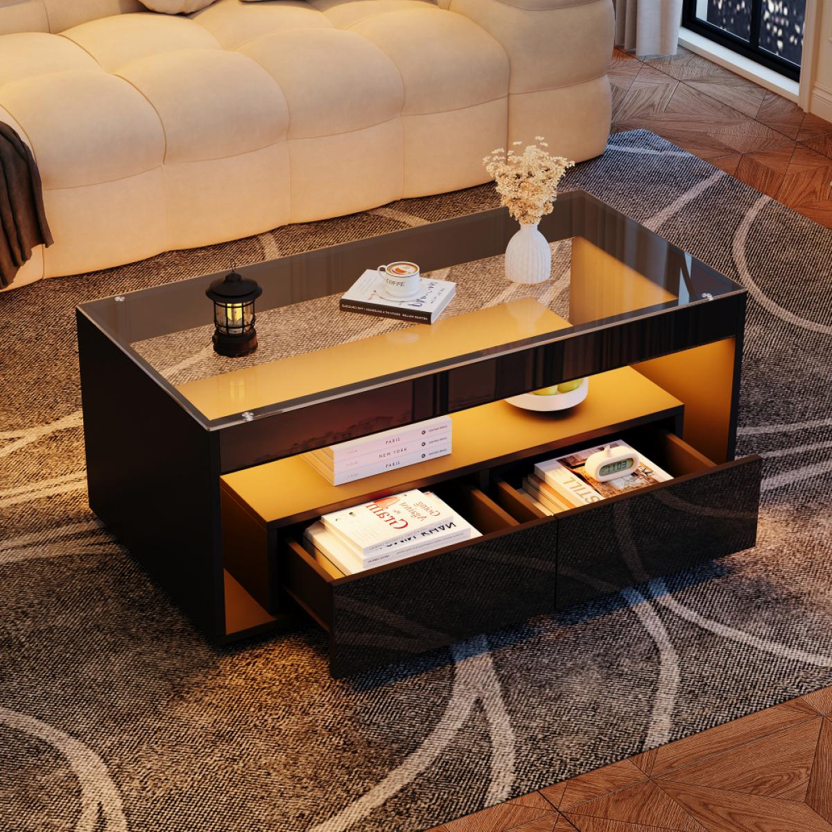 Ein moderner Couchtisch mit Glasplatte. Er hat Schubladen mit Büchern, eine Lampe, eine Vase und ein beiges Sofa im Hintergrund.