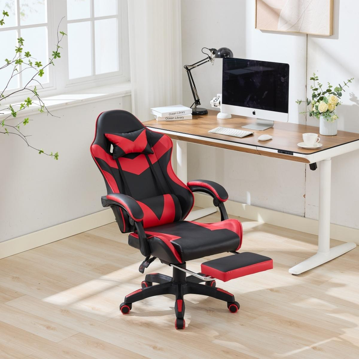 Ein Gaming-Stuhl, rot und schwarz, vor einem Schreibtisch mit Computer und Lampe. Links ein Fenster mit grünen Blättern.