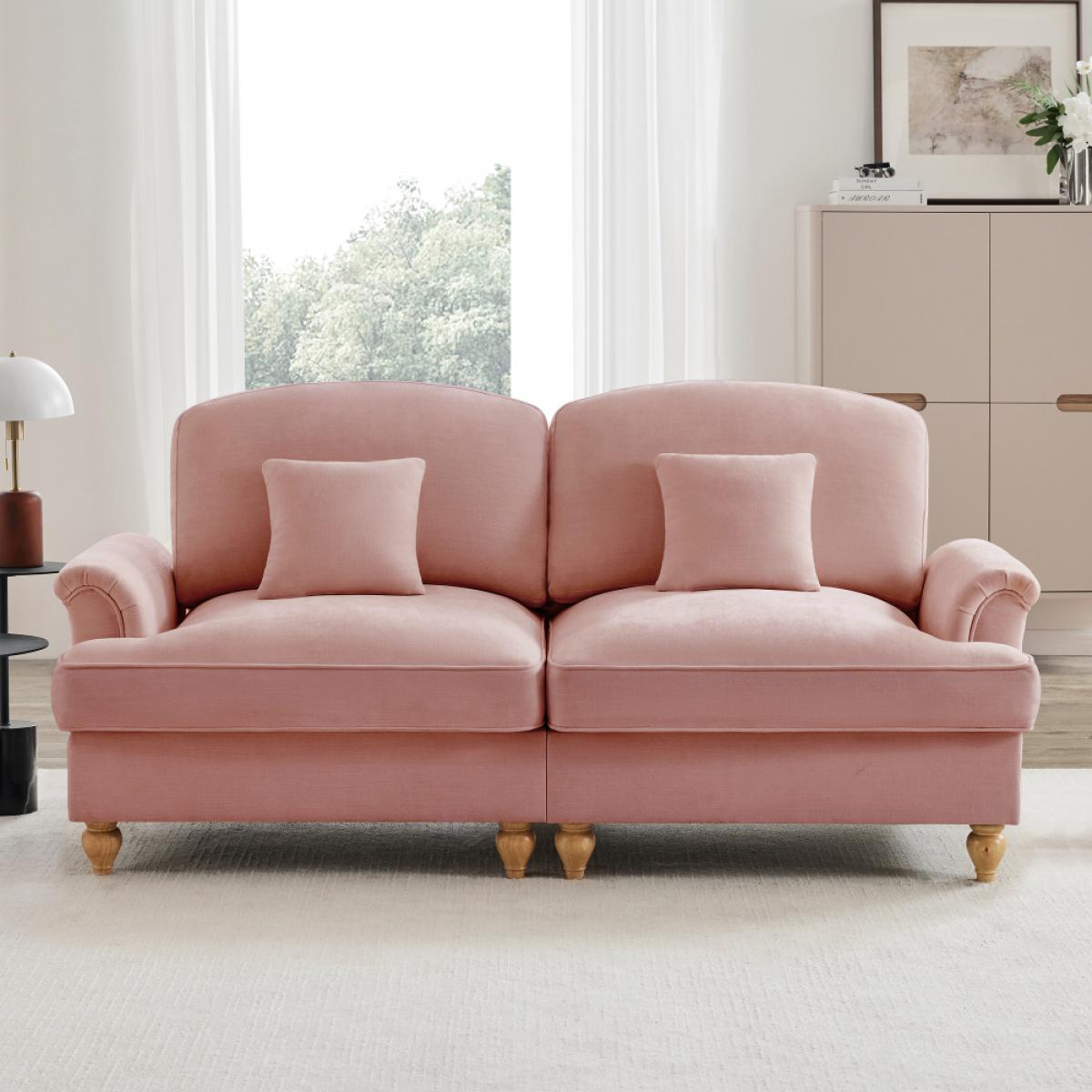 Rosa Sofa mit zwei Kissen in einem Raum mit Fenster. Ein Schrank mit Dekoration ist sichtbar. Die Szene ist hell und luftig.