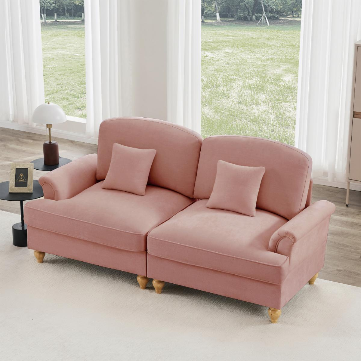 Ein rosafarbenes Sofa mit zwei Kissen steht auf einem weißen Teppich. Dahinter offenbart ein Fenster mit transparenten Vorhängen einen grünen Garten.
