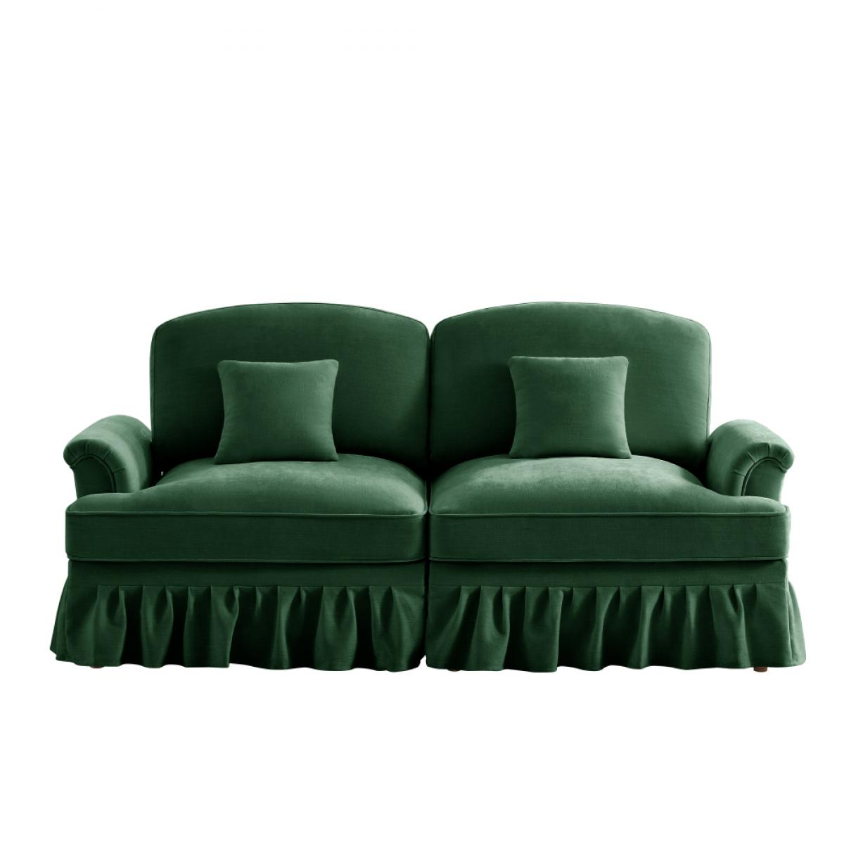 Ein grünes Samtsofa mit zwei Kissen und Rüschenrock vor weißem Hintergrund.