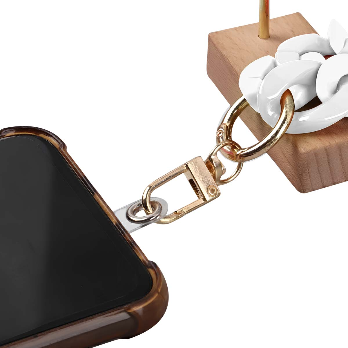 Un telefono in una custodia marrone con una catena d'oro collegata. Una catena bianca è attaccata a un blocco di legno.