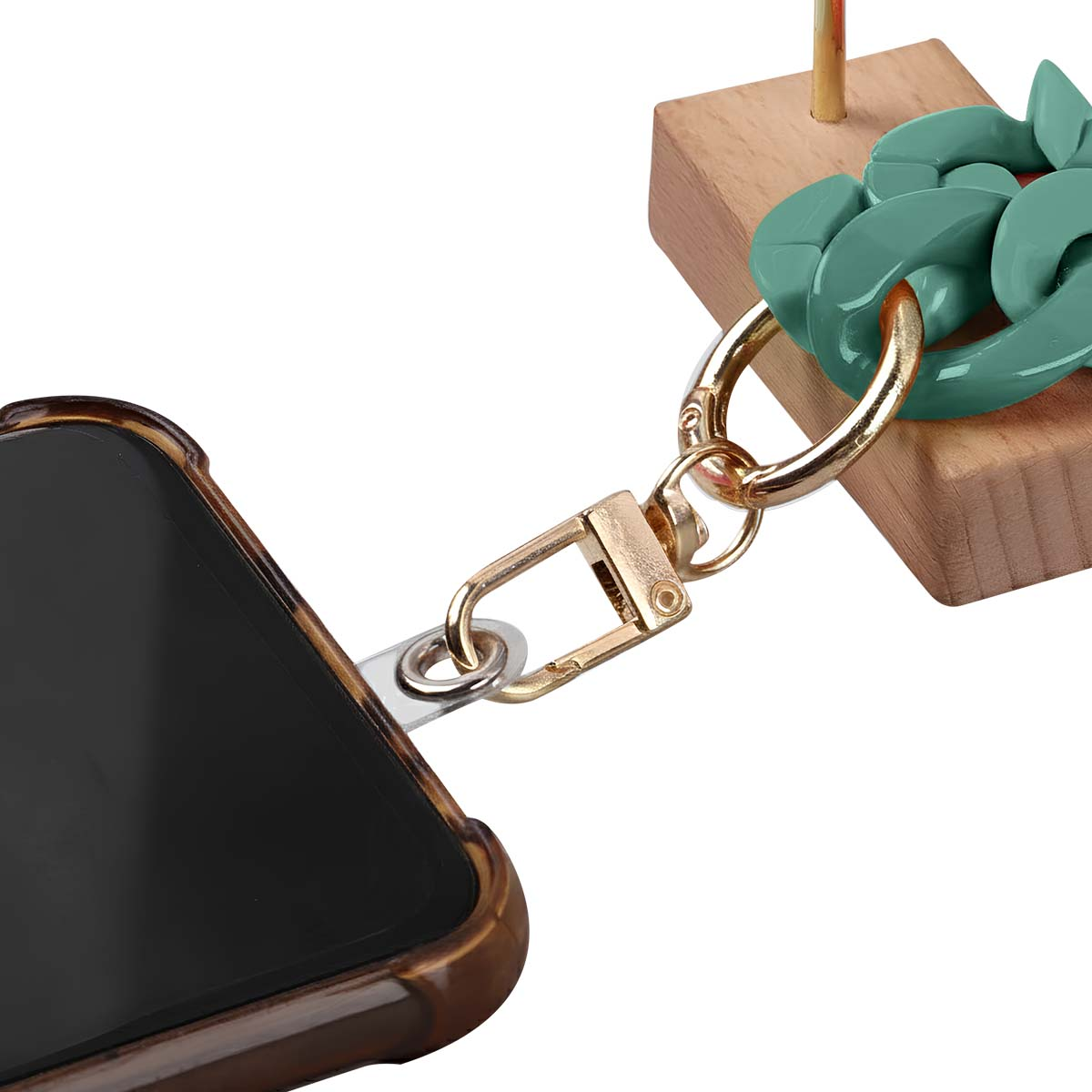 Una custodia per telefono è collegata a una catena e a un fermaglio dorati, con una catena verde acqua e un blocco di legno sullo sfondo.