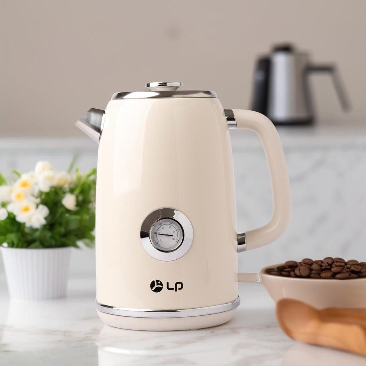 Cremefarbener Wasserkocher mit Temperaturanzeige, neben einer Schale mit Kaffeebohnen und einer kleinen Pflanze, auf Marmoroberfläche.