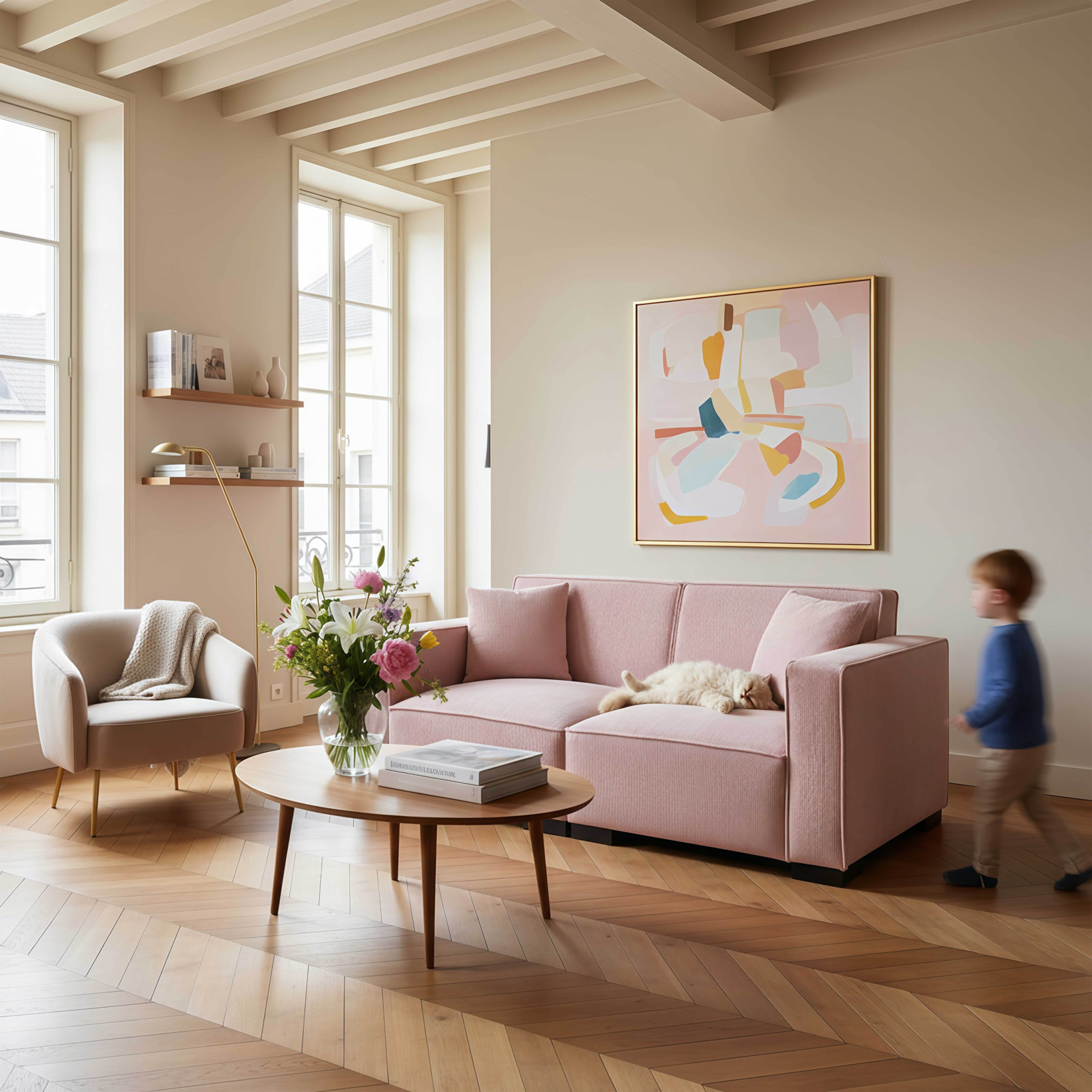 Wohnzimmer mit rosa Sofa, Kunstwerk und Kind. Katze liegt auf dem Sofa. Holzboden.