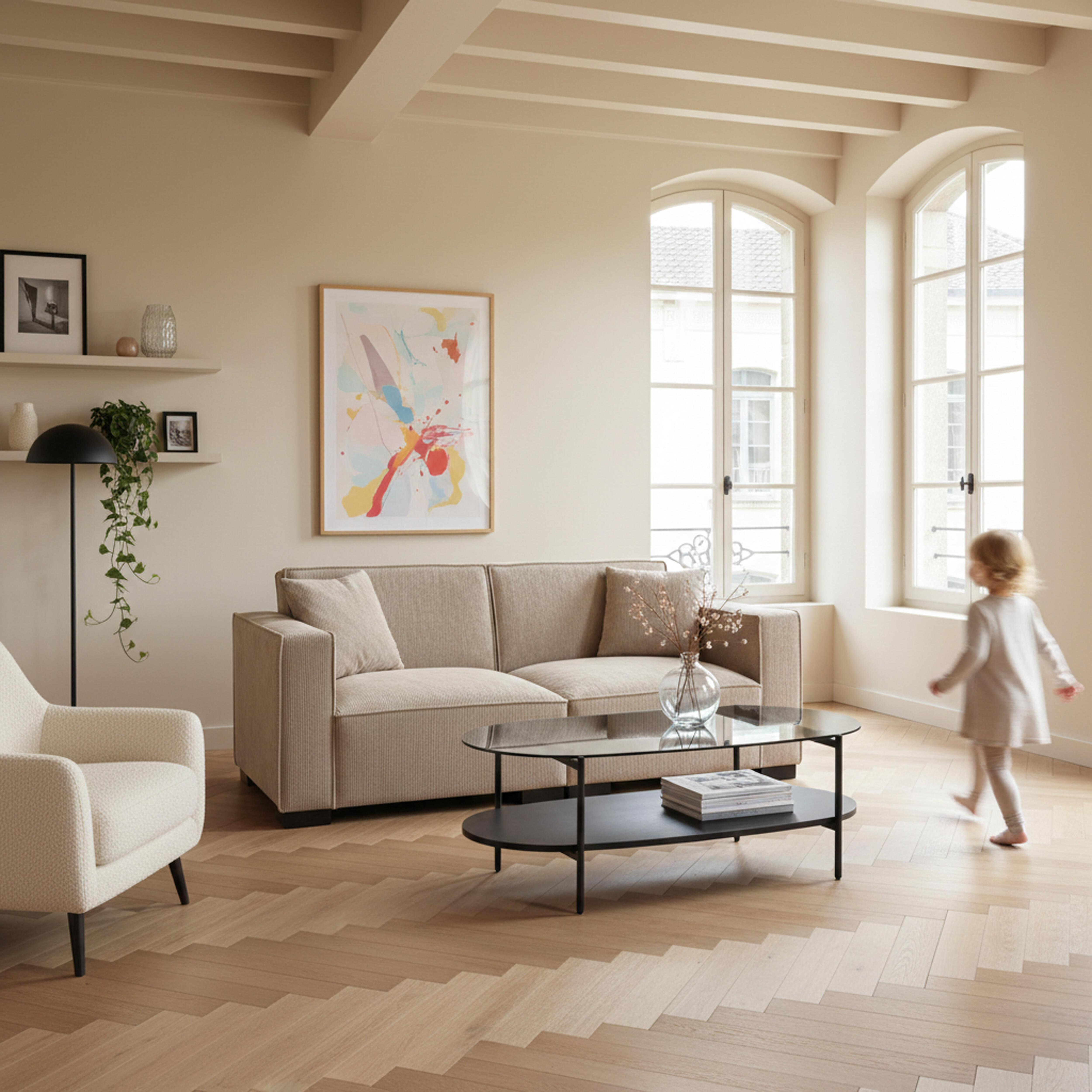 Wohnzimmer mit beigem Sofa, Sessel, Couchtisch, Kunst und einem Kind, das zum Fenster geht.