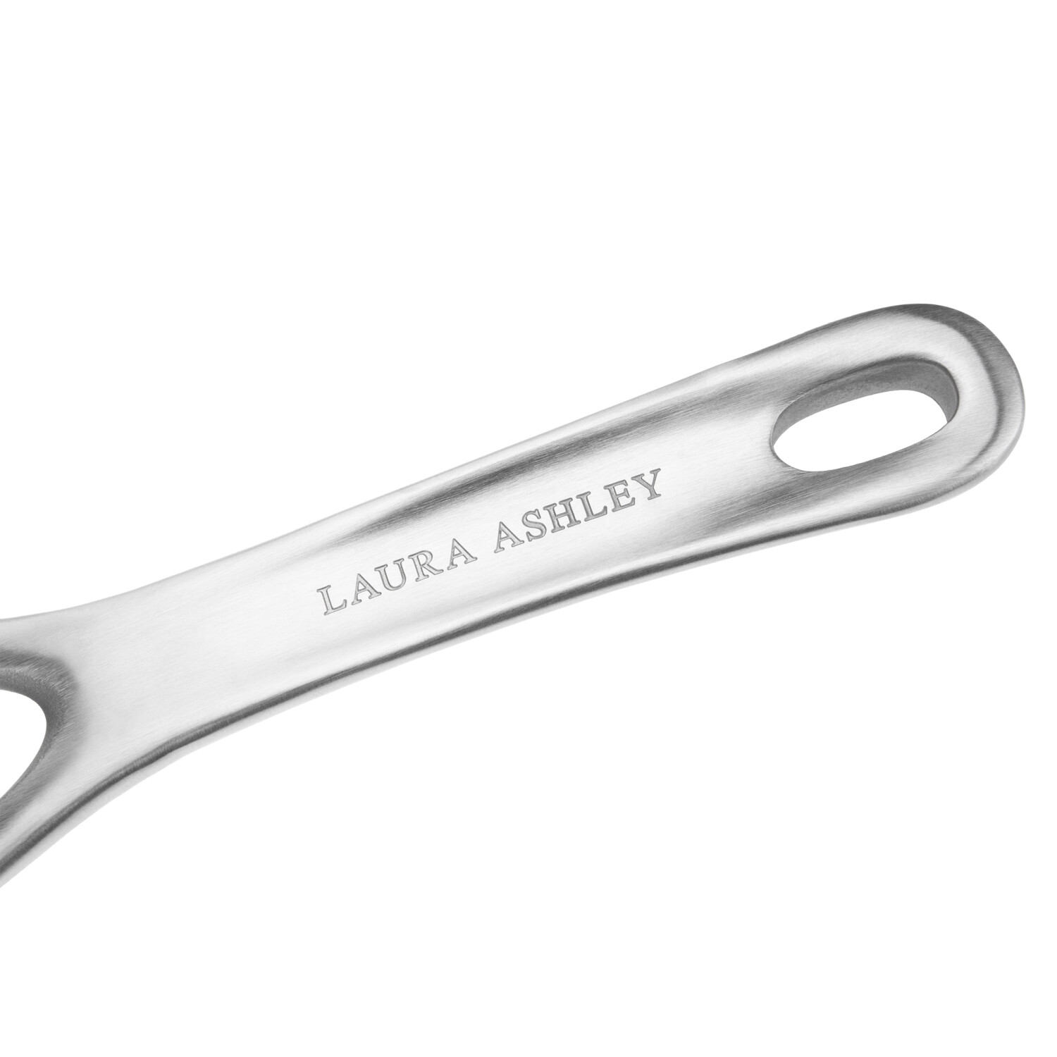 Nahaufnahme eines silbernen Pfannengriffs mit der Aufschrift 'LAURA ASHLEY' und einem Loch. Der Hintergrund ist weiß.