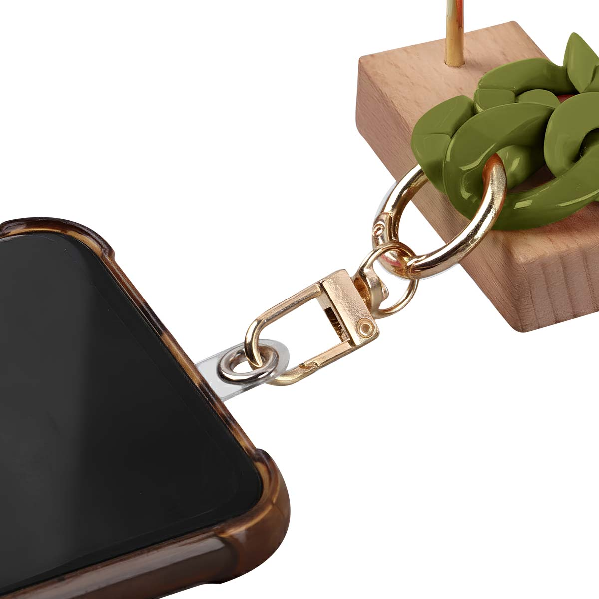 Un telefono in una custodia marrone è attaccato a una catena d'oro e a maglie verdi. Un blocco di legno è sullo sfondo.