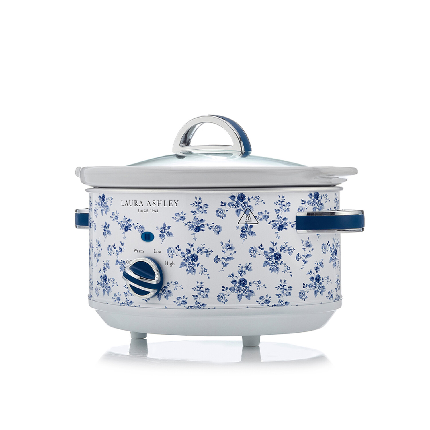 Ein weißer Schongarer mit blauem Blumendesign und Glasdeckel. Er hat einen Griff und einen Wahlschalter.