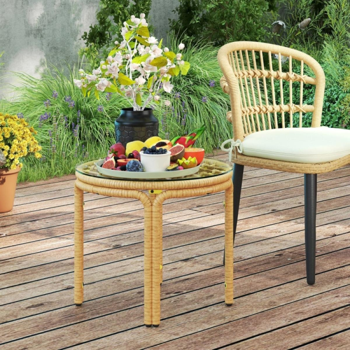 Ein Rattantisch mit Obst steht auf einer Holzterrasse. Daneben steht ein Stuhl. Blumen und Pflanzen sind im Hintergrund.