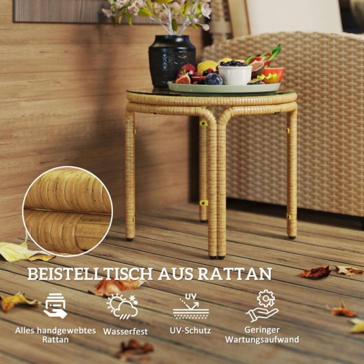 Ein Beistelltisch aus Rattan mit Glasplatte trägt einen Obstteller und eine schwarze Vase mit Blumen. Holzterrasse im Vordergrund.