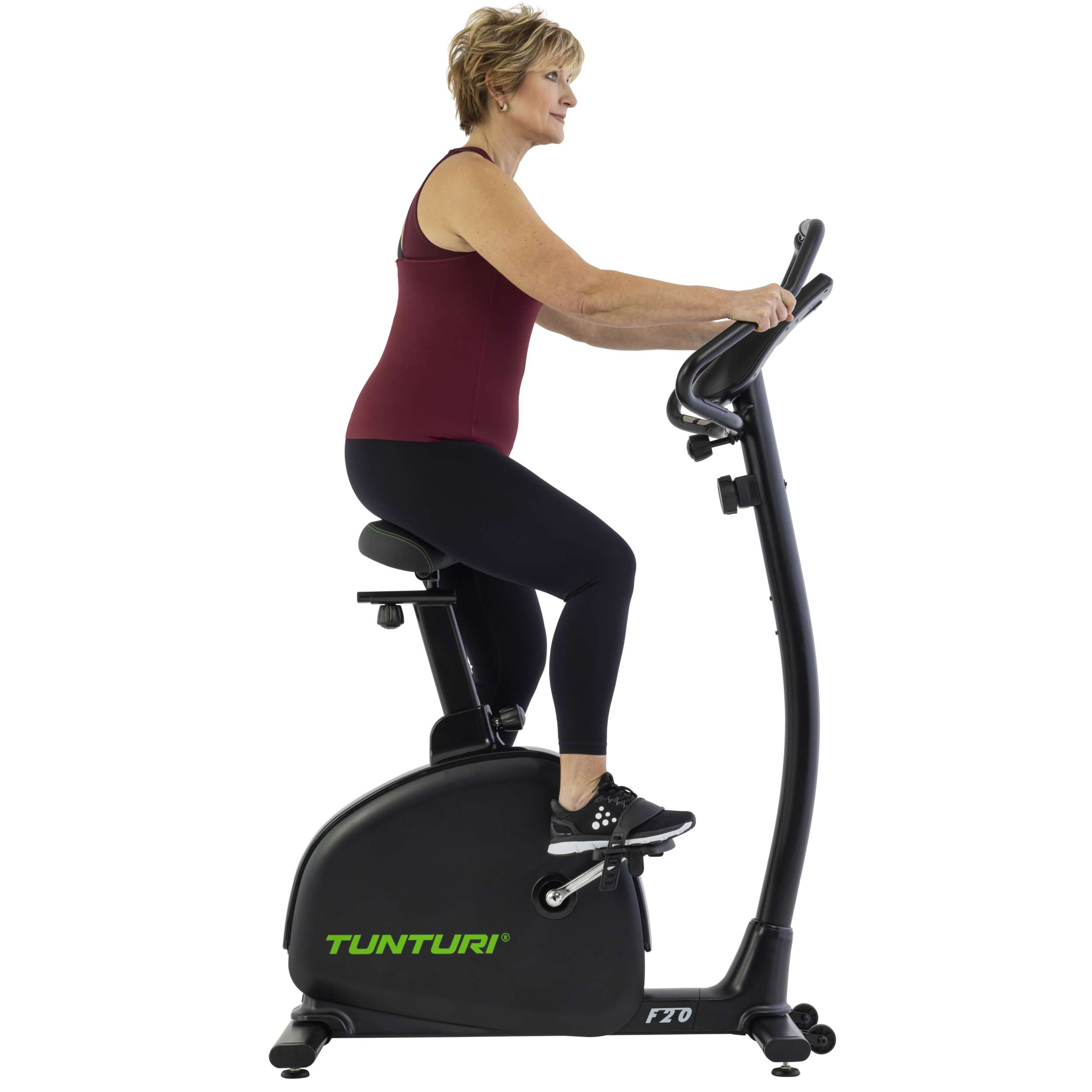 Vrouw op hometrainer. Ze draagt een zwarte legging en een bordeauxrode top. De fiets is zwart.