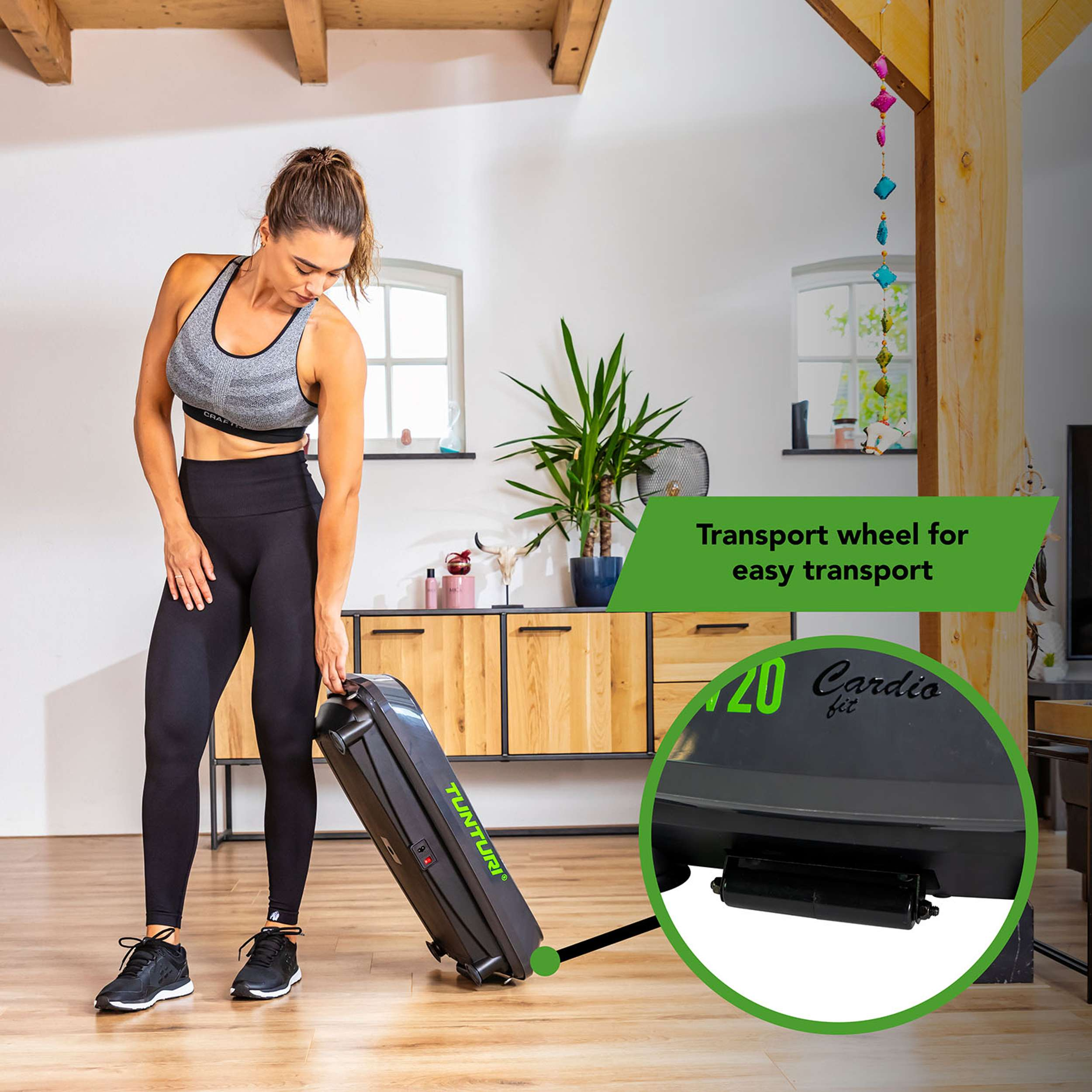Vrouw in sportkleding trekt een cardio fit machine. Houten vloer en meubels op de achtergrond.