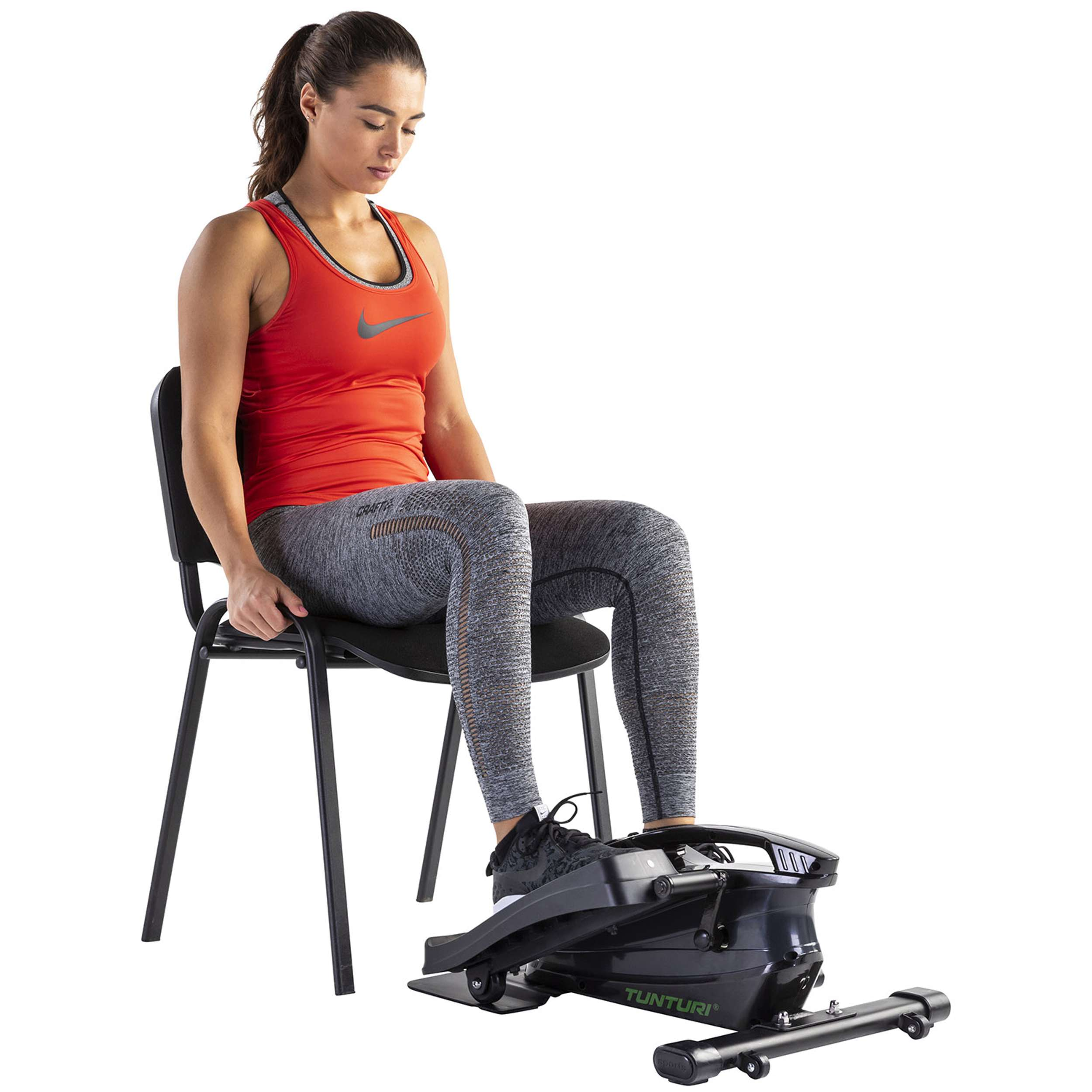 Vrouw in rode top en grijze legging op een stoel met een zwarte Tunturi stepper. Witte achtergrond.