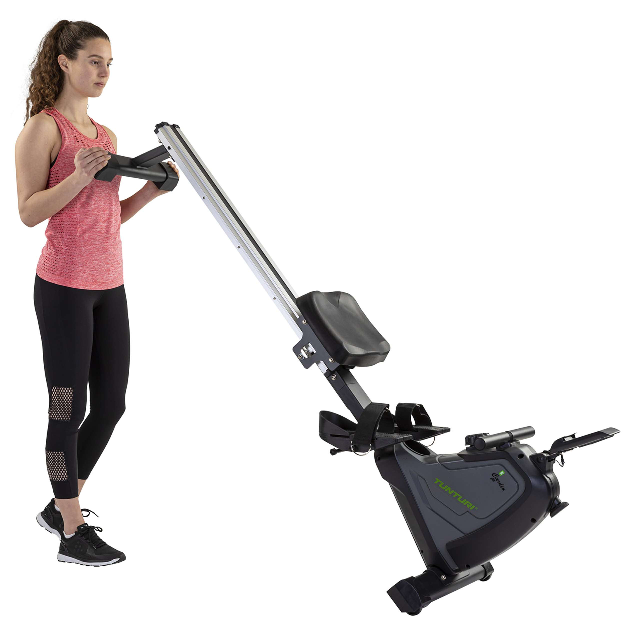 Vrouw in sportkleding staat bij een roeimachine. Machine is zwart en grijs. Achtergrond is wit.