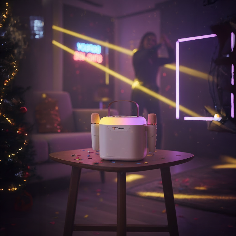 Bir karaoke makinesi ve mikrofonlar masada duruyor. Arka planda bir kişi şarkı söylüyor. Bir Noel ağacı ve neon ışıklar görülebilir.