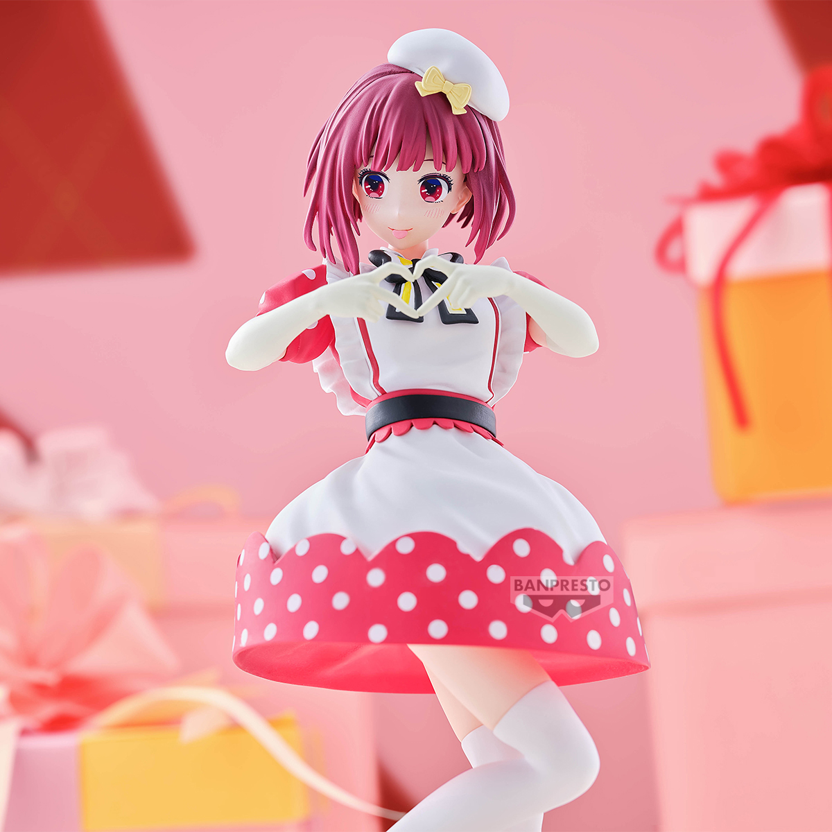 Figura de anime con traje de doncella haciendo forma de corazón. Vestido blanco con lunares rojos. Fondo rosa con cajas de regalo.