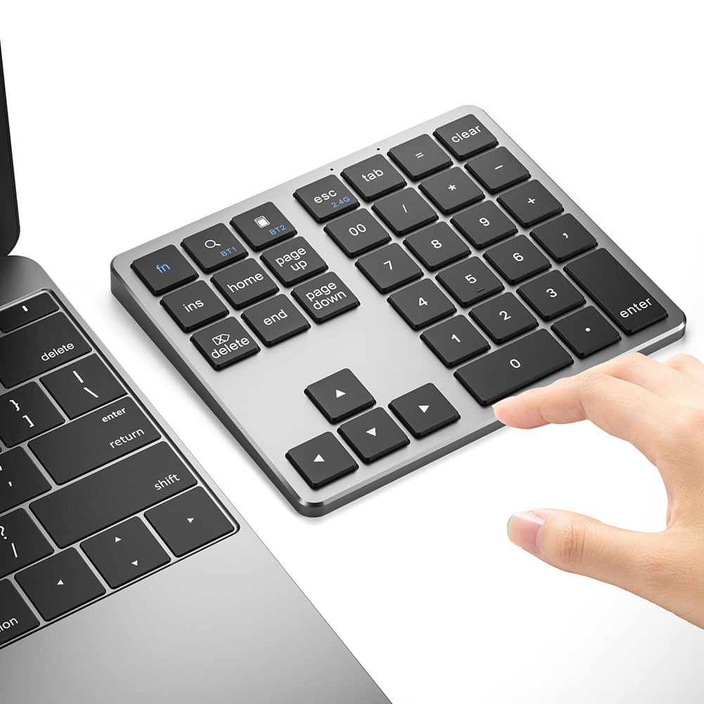Eine Hand drückt die '0'-Taste auf einem silbernen Ziffernblock. Eine Laptop-Tastatur ist links sichtbar.