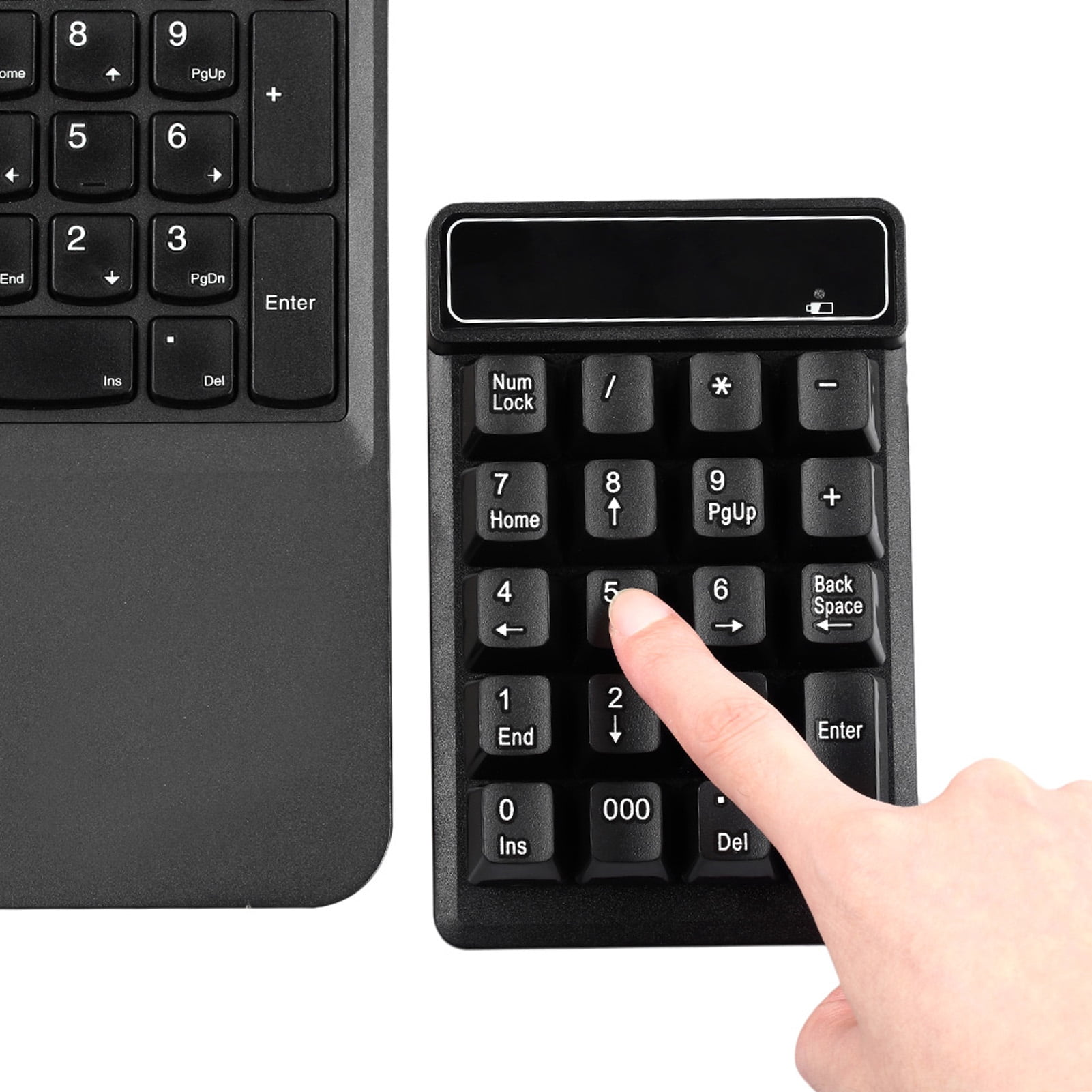 Eine Hand drückt die Taste '5' auf einem schwarzen Nummernblock. Ein Teil einer Tastatur ist links sichtbar.