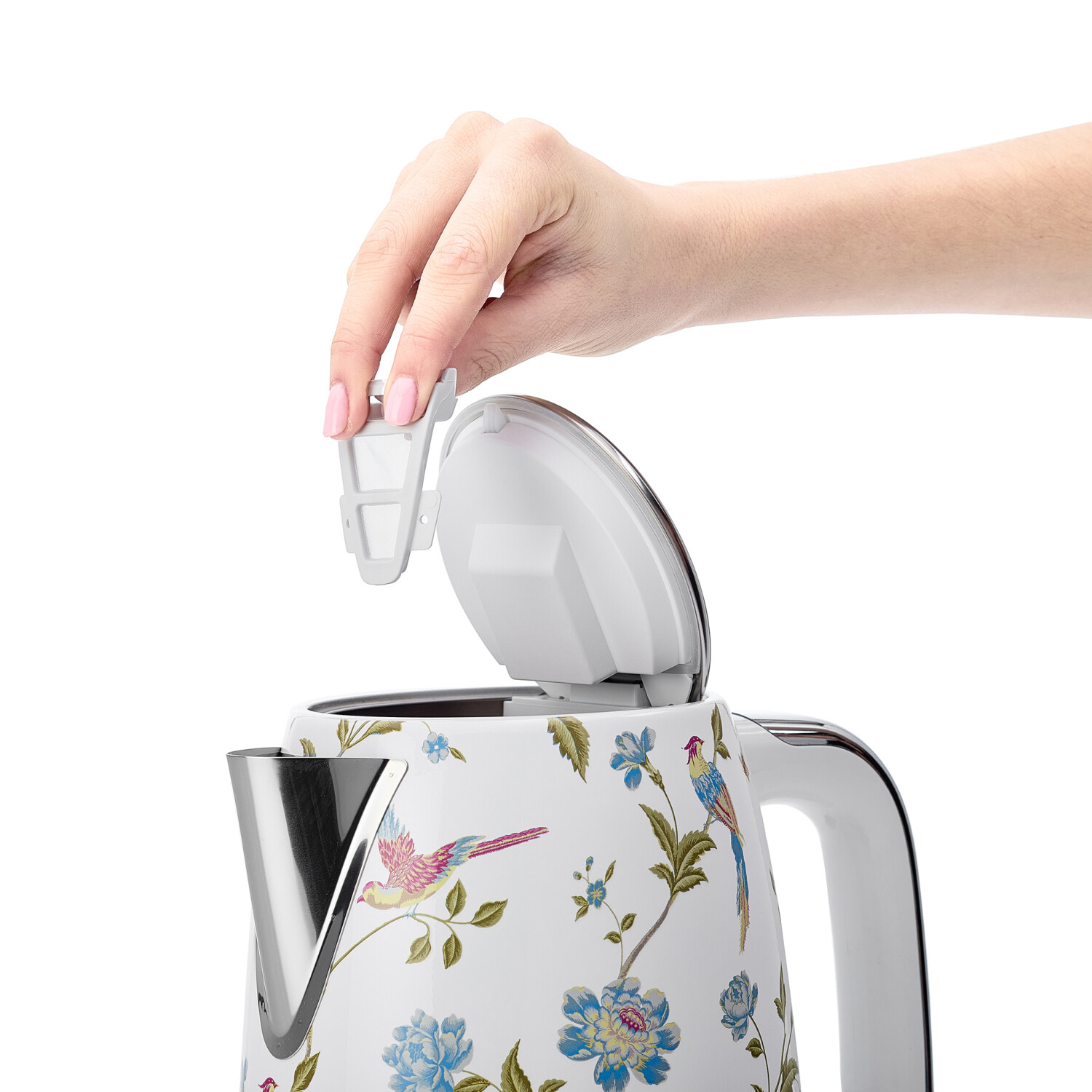 Eine Hand hebt einen weißen Filter von einem floral dekorierten Wasserkocher. Der Wasserkocher hat einen teilweise geöffneten Deckel.