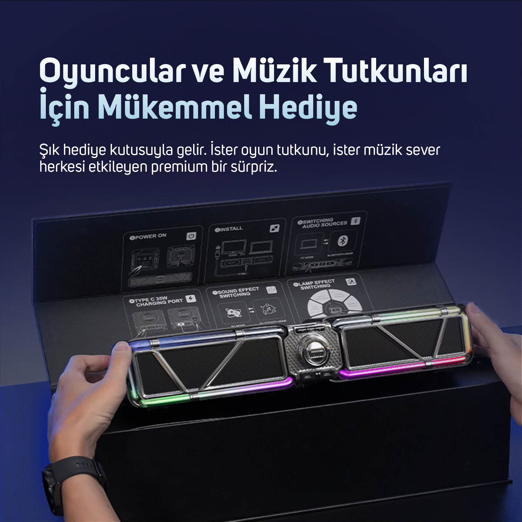 Bir kişi siyah bir kutu içinde bir hoparlör tutuyor. Hoparlör renkli ışıklara ve metalik bir tasarıma sahip.