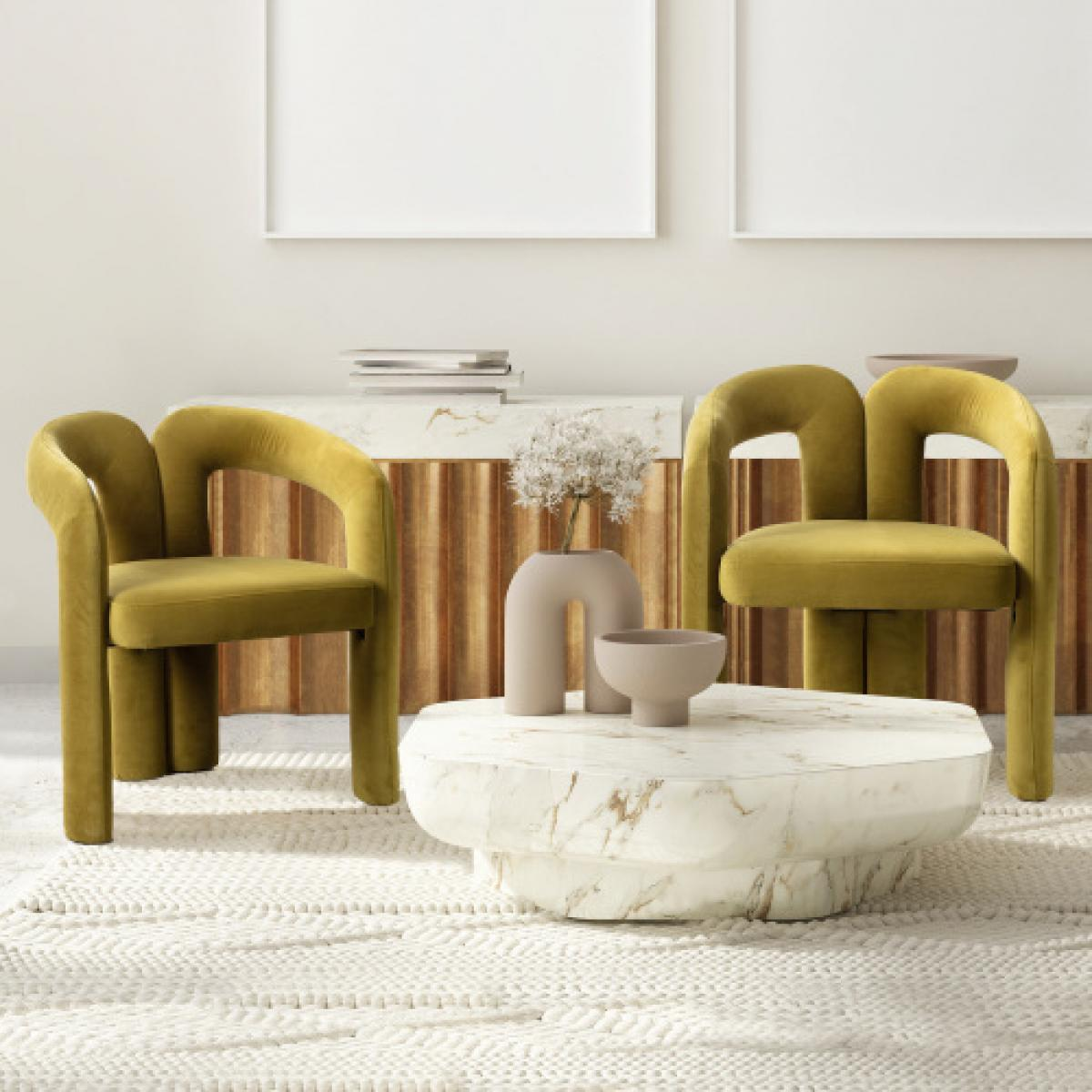 Zwei olivgrüne Stühle stehen vor einem Marmor-Couchtisch mit Vase und Schale. Der Teppich ist weiß. Im Hintergrund Holzverkleidung und Kunst.