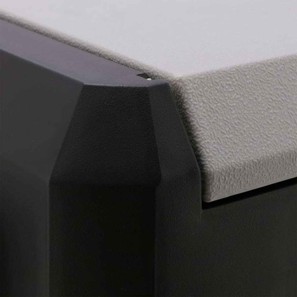 Close-up of a black and gray plastic corner. The black part is textured, while the gray has a textured surface. The edge is smooth.