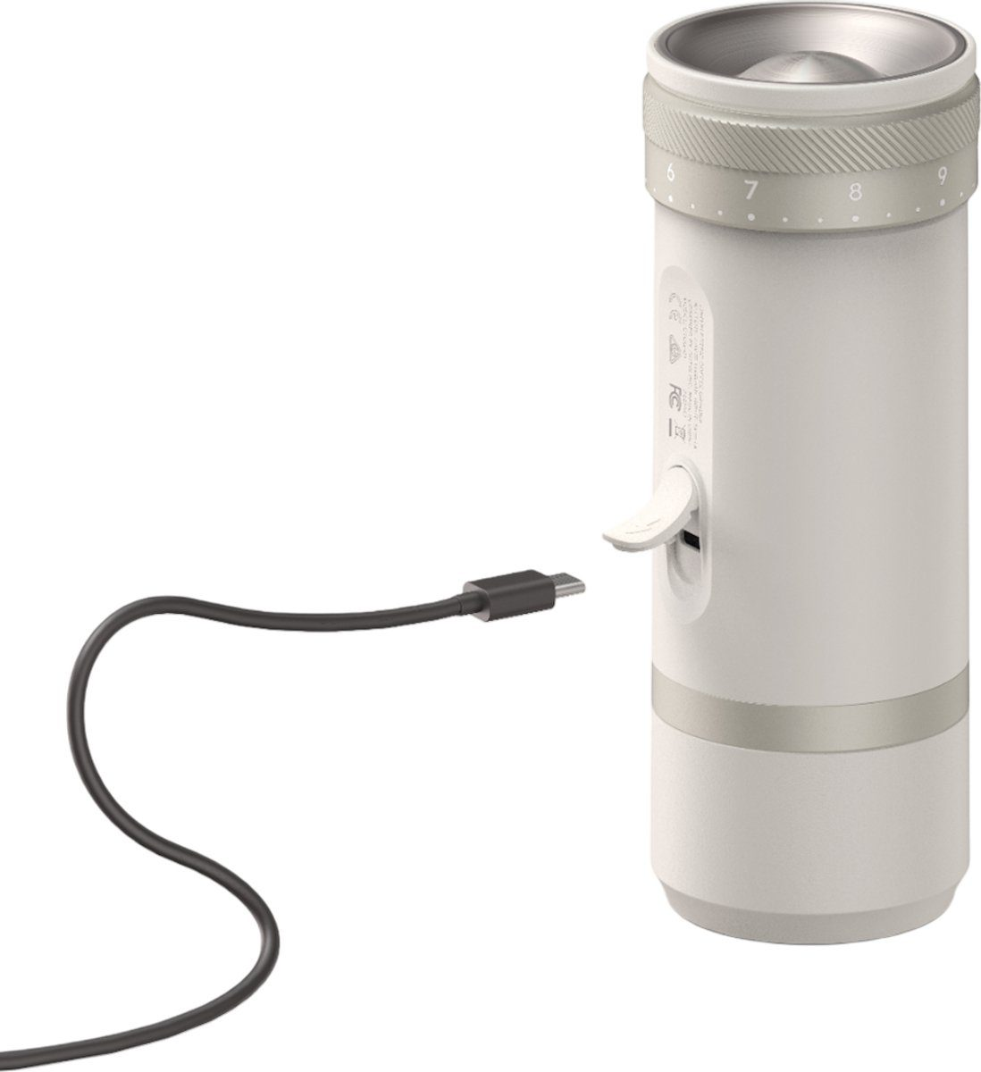 Biały i srebrny elektryczny młynek do kawy z podłączonym kablem ładującym. Młynek ma tarczę.