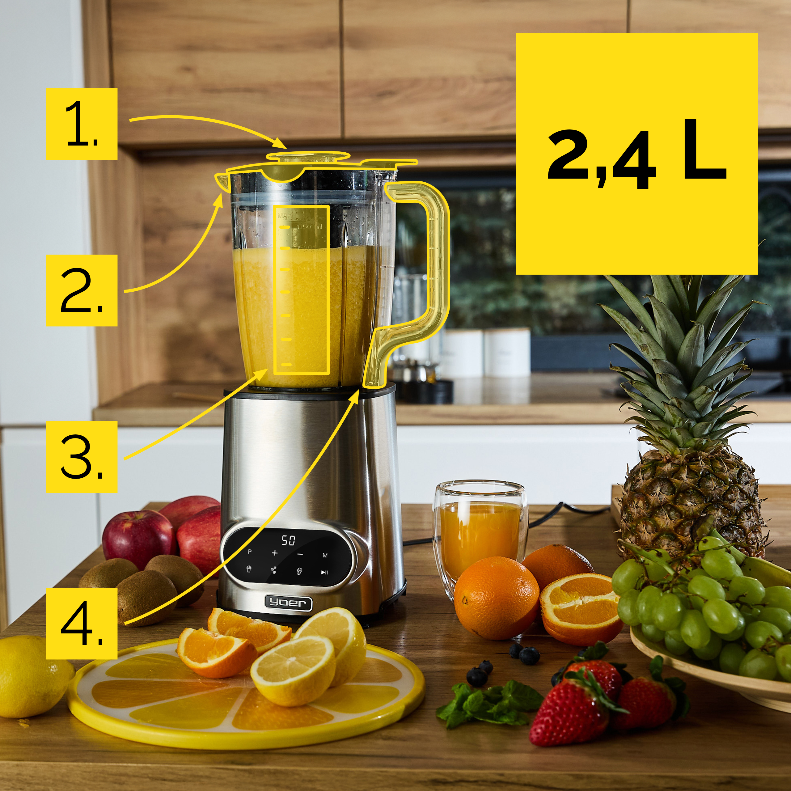 Blender z sokiem stoi na drewnianym blacie z owocami i ananasem. Blender jest srebrny.