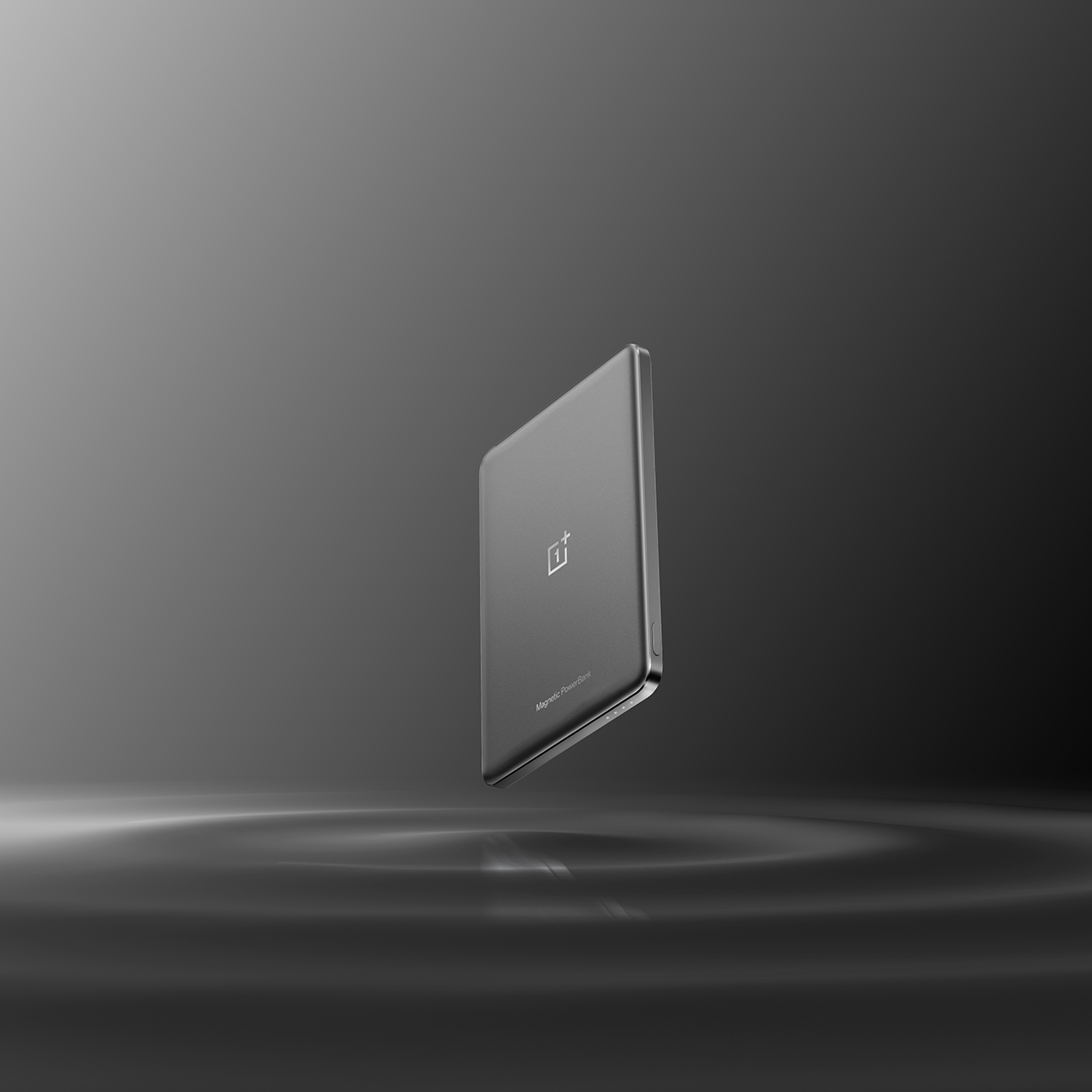 Eine graue OnePlus-Magnet-Powerbank schwebt in der Luft, das OnePlus-Logo ist sichtbar. Der Hintergrund ist ein Grauton.