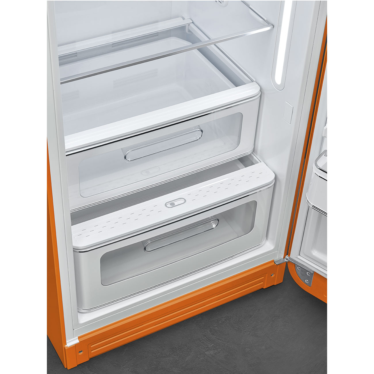 Refrigerador naranja abierto con interior blanco. Contiene cajones y estantes. Puerta abierta, mostrando el interior. Suelo gris oscuro en el fondo.