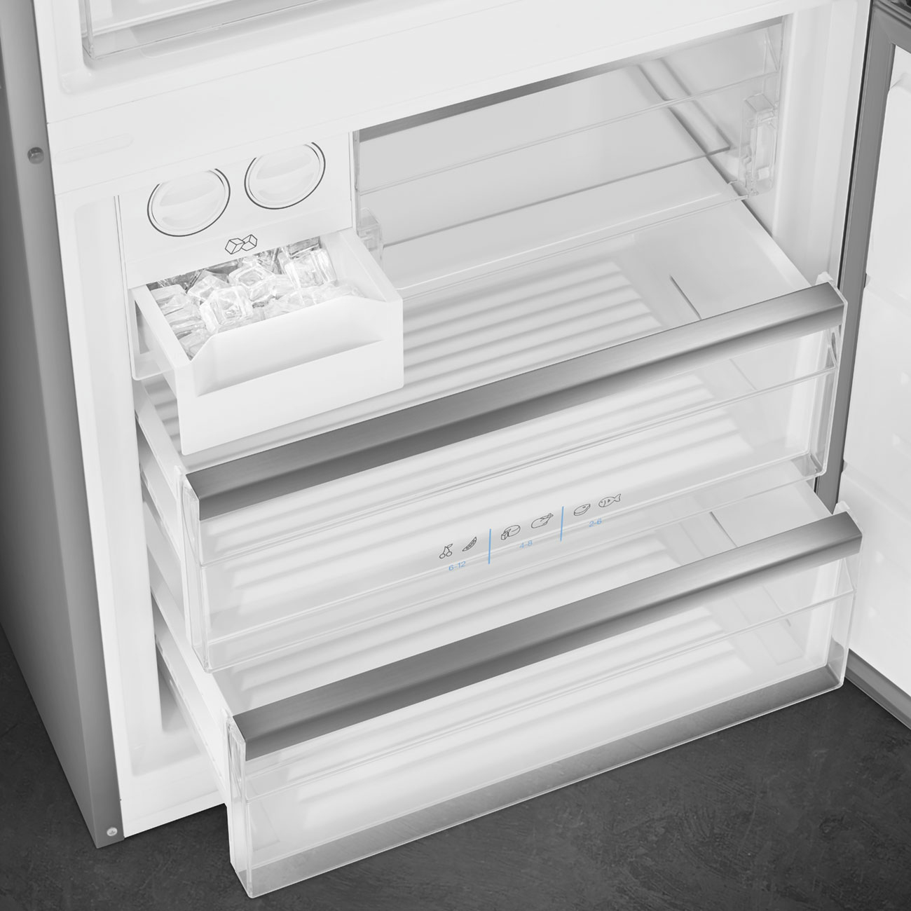 Frigorifero aperto con cassetti, fabbricatore di ghiaccio e ripiani. Cassetti trasparenti. Fabbricatore di ghiaccio con cubetti. Interno bianco.